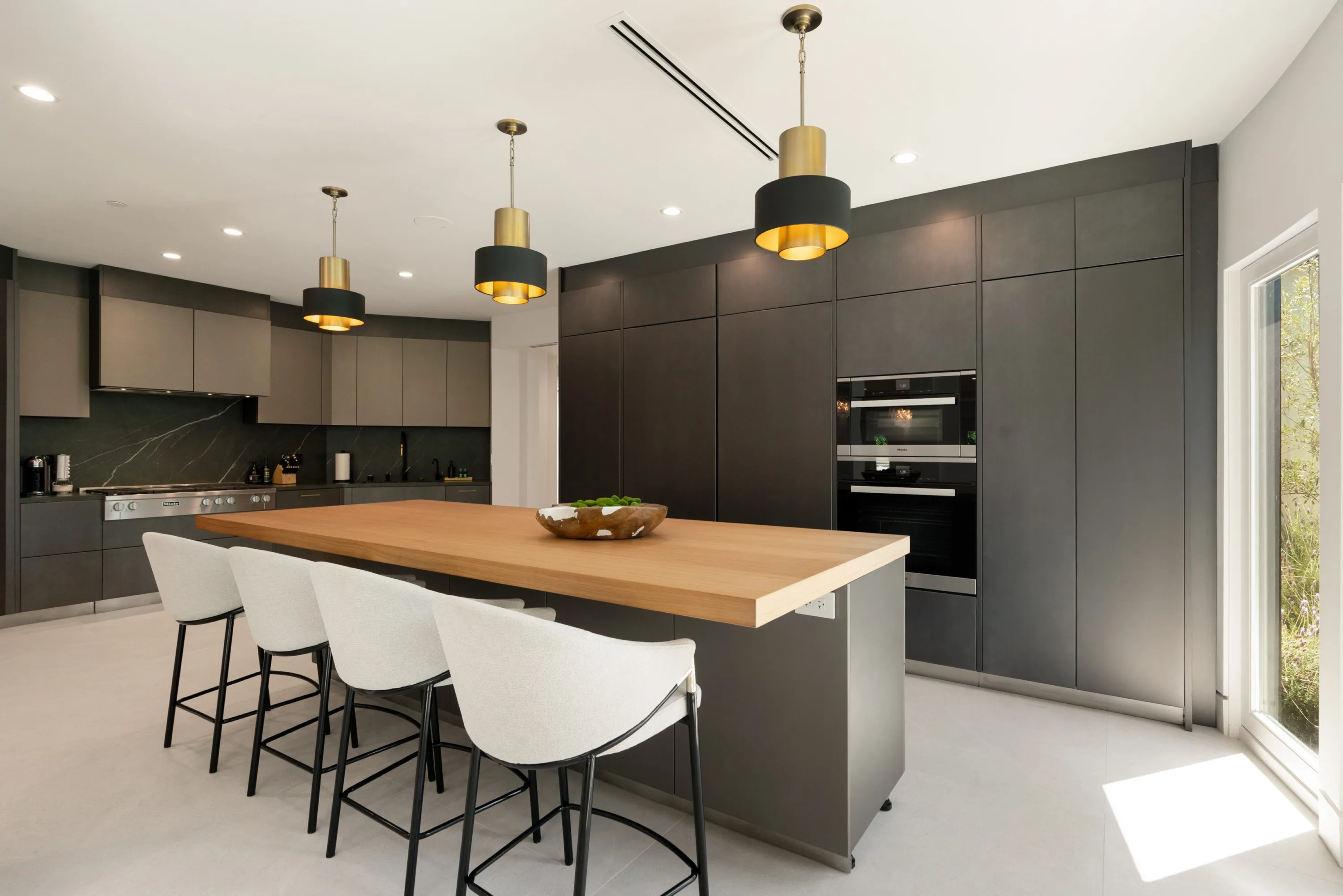 Chef's kitchen in graphite cabinetry with oak island, four stools, range and double wall ovens