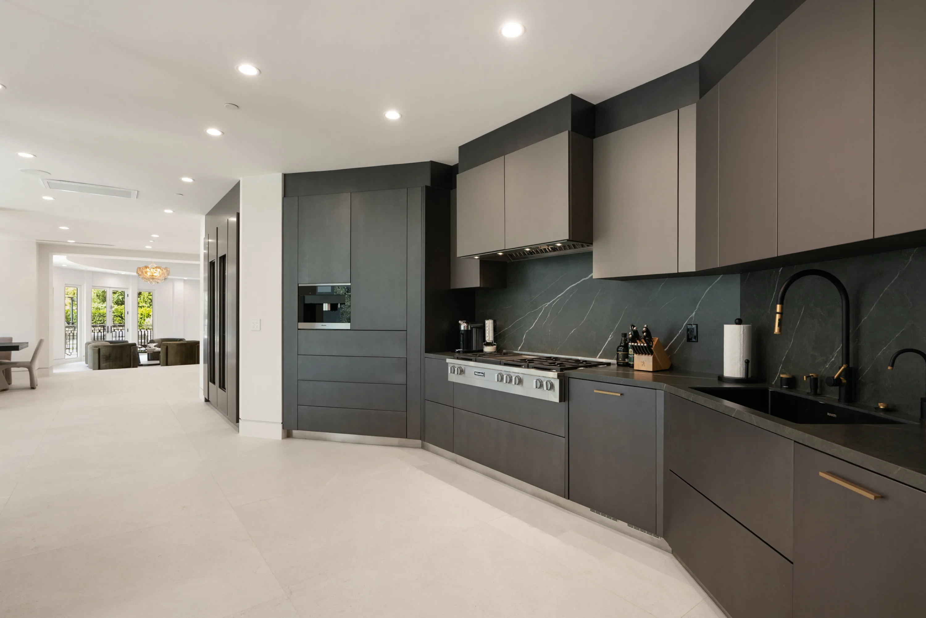 Cook's run with gas range, veined stone backsplash and sink, sightline through to the living room