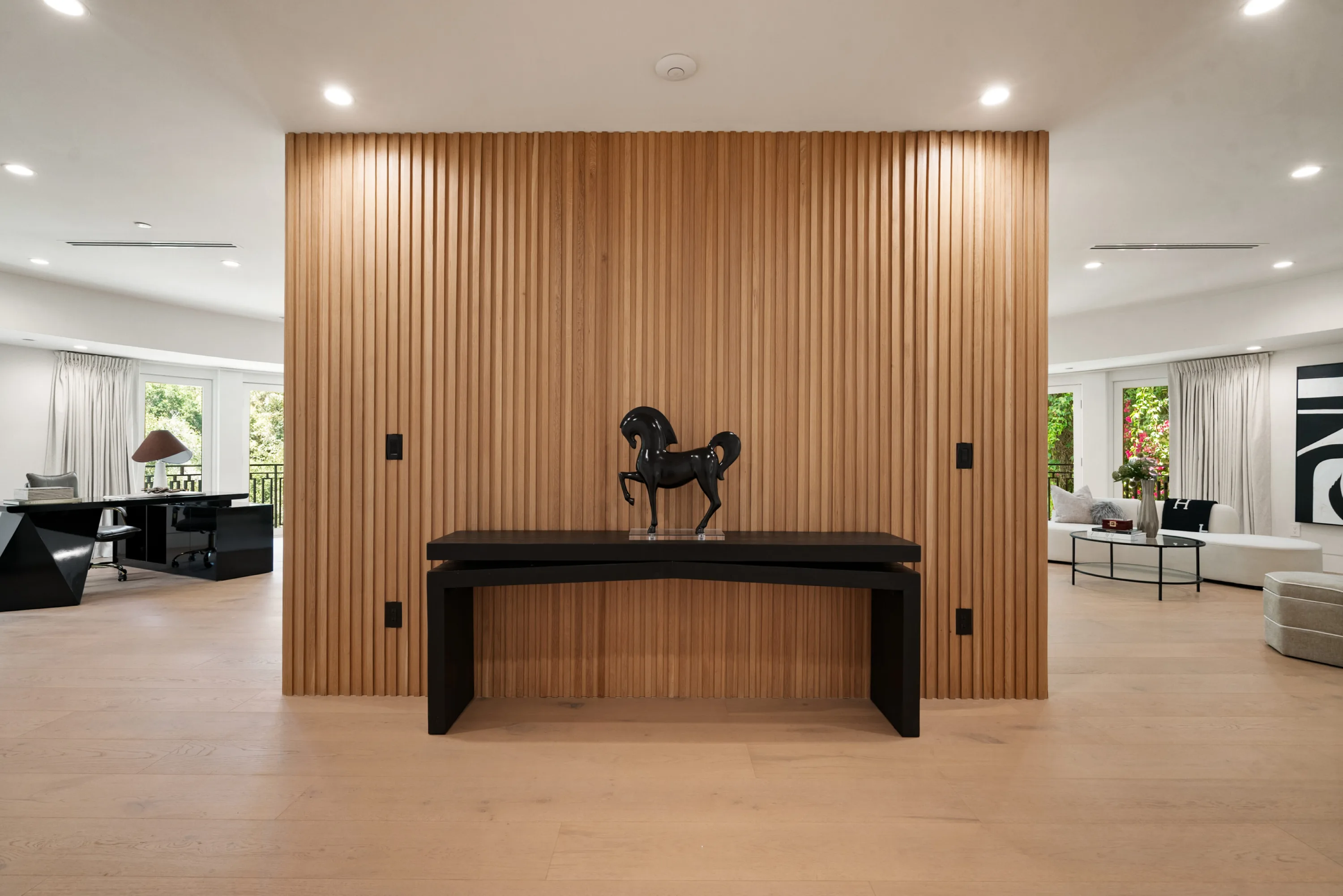 Slatted oak partition with console and horse sculpture dividing an upstairs study from a seating area