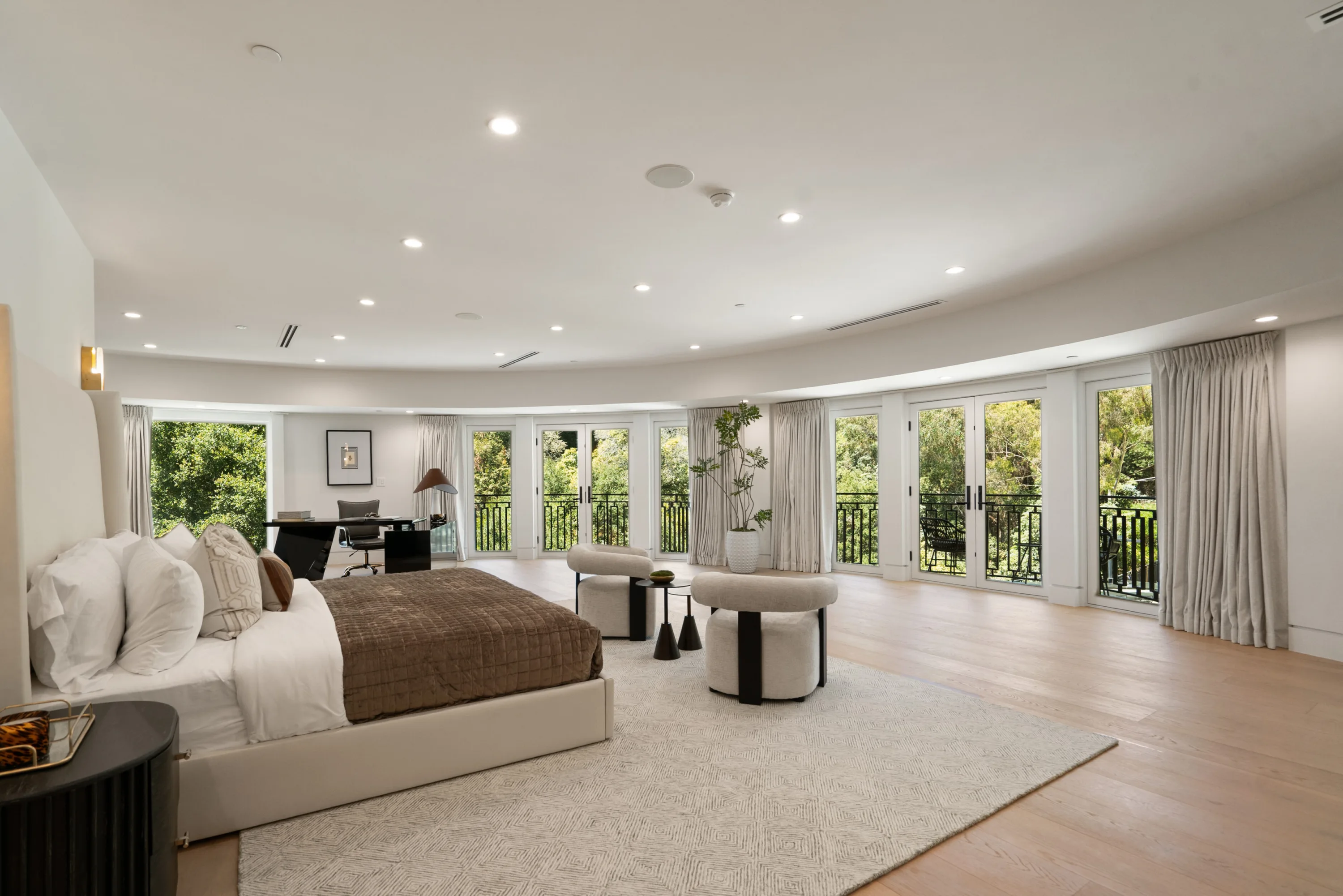 Primary suite with curved wall of French doors to Juliet balconies, treetop outlook and desk nook