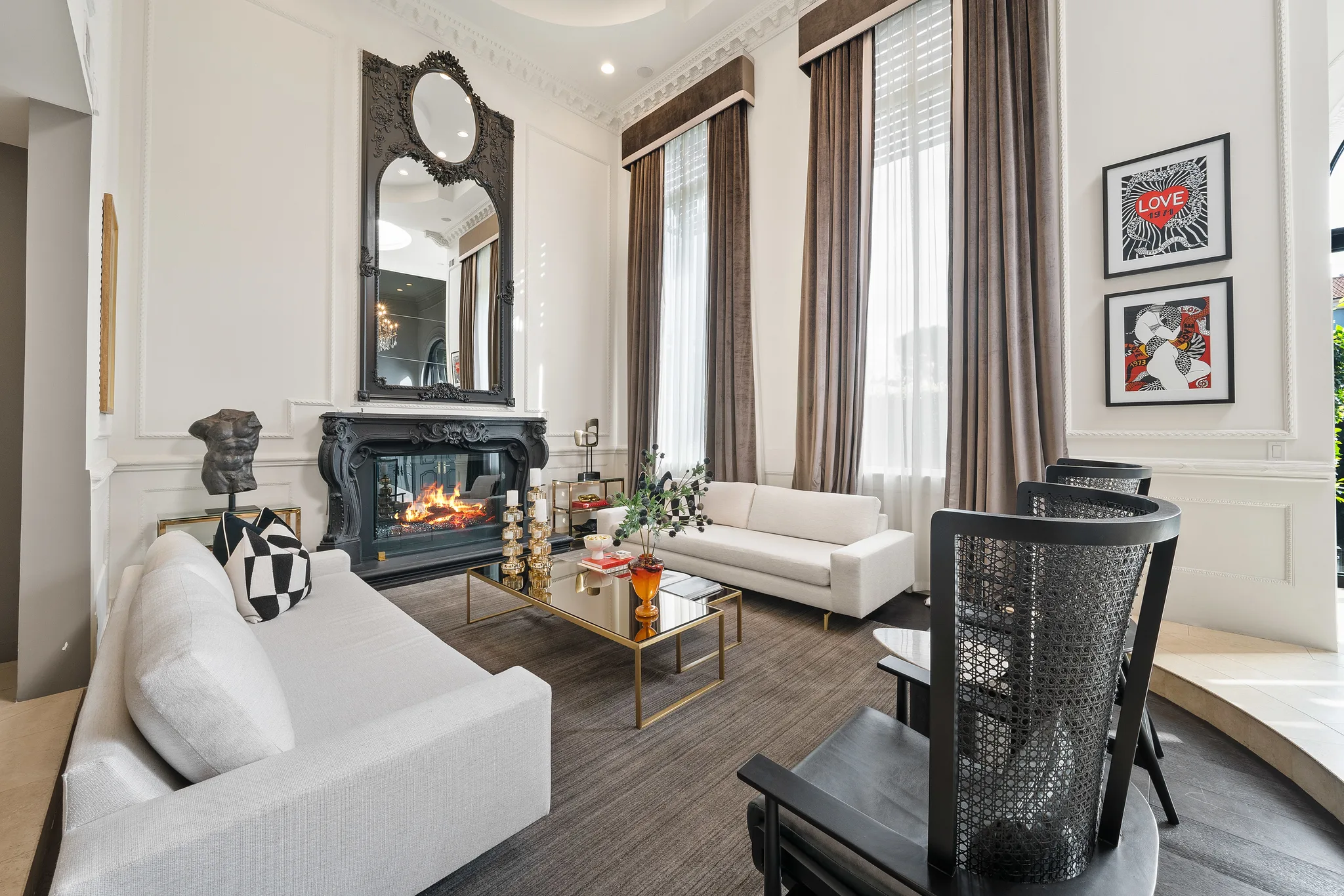 Formal salon seating with ornate mirror above the fire and tall windows framing the garden