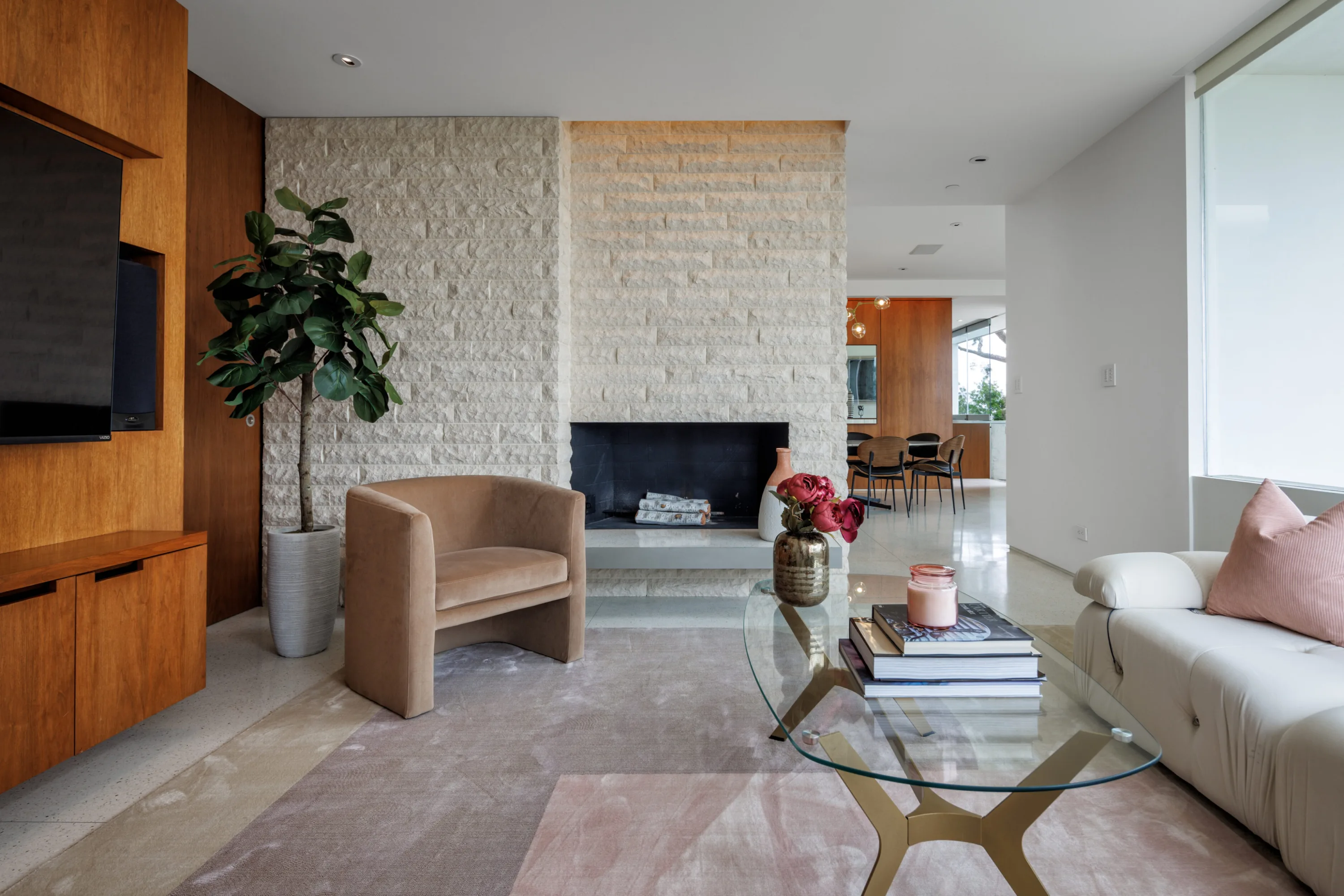 Family lounge with stone fireplace, wall-mounted TV in walnut joinery and glass coffee table