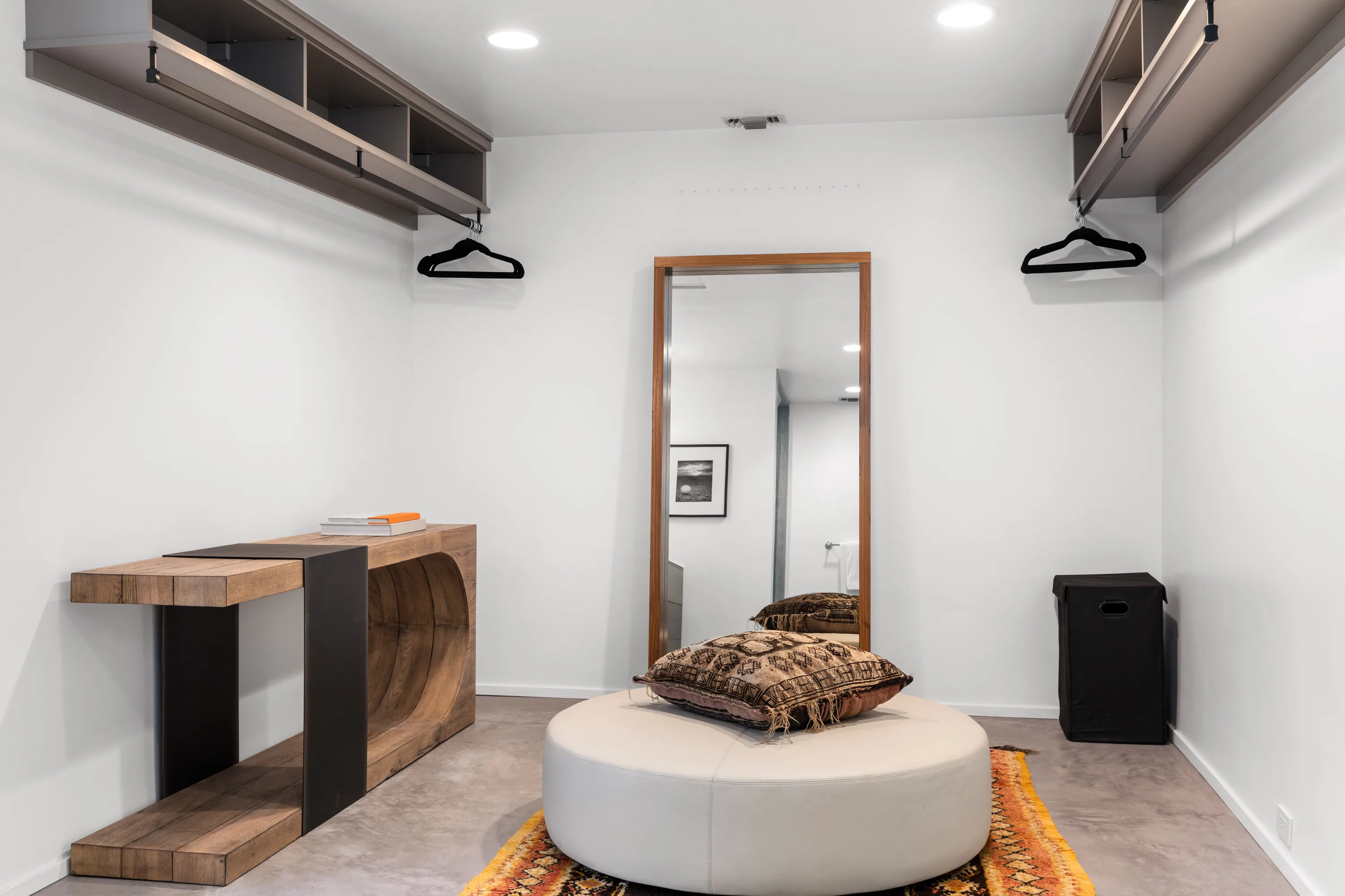 Dressing room with open hanging rails, full-length mirror and round leather ottoman on a Moroccan rug