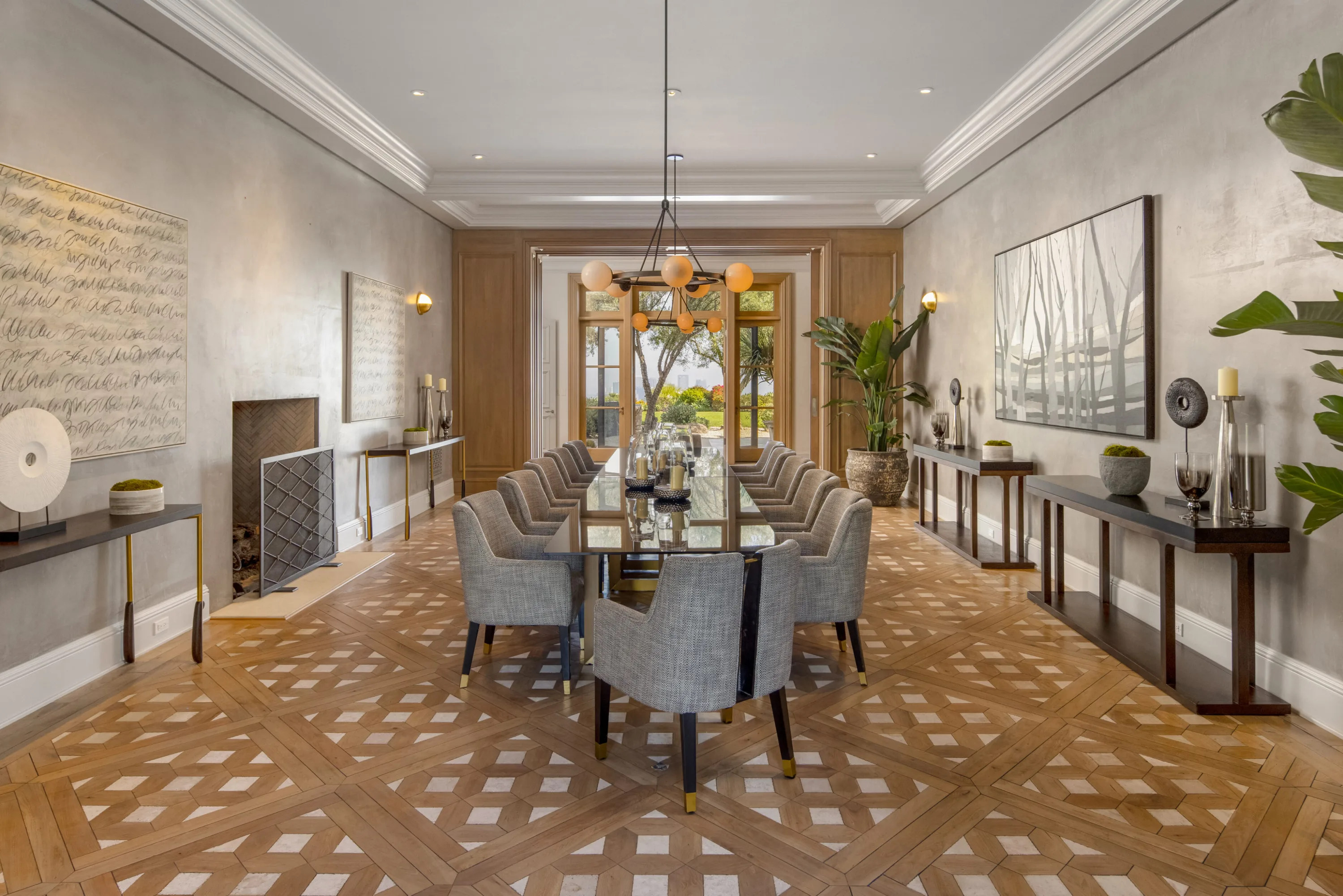 Formal dining room seating twelve on patterned parquet, fireplace and garden doors at the far end