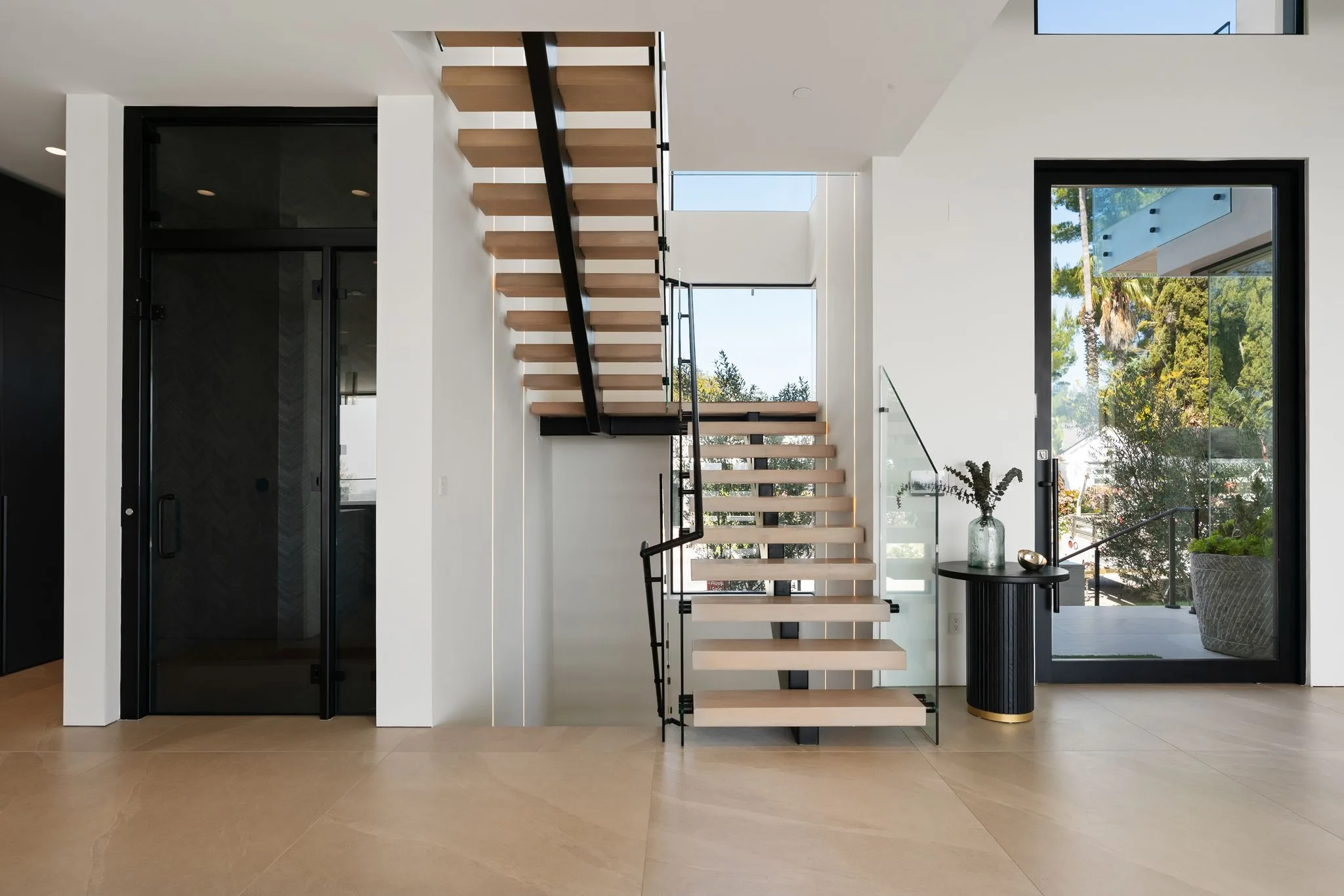 Entry hall with floating oak-and-glass staircase and a glazed door to the garden