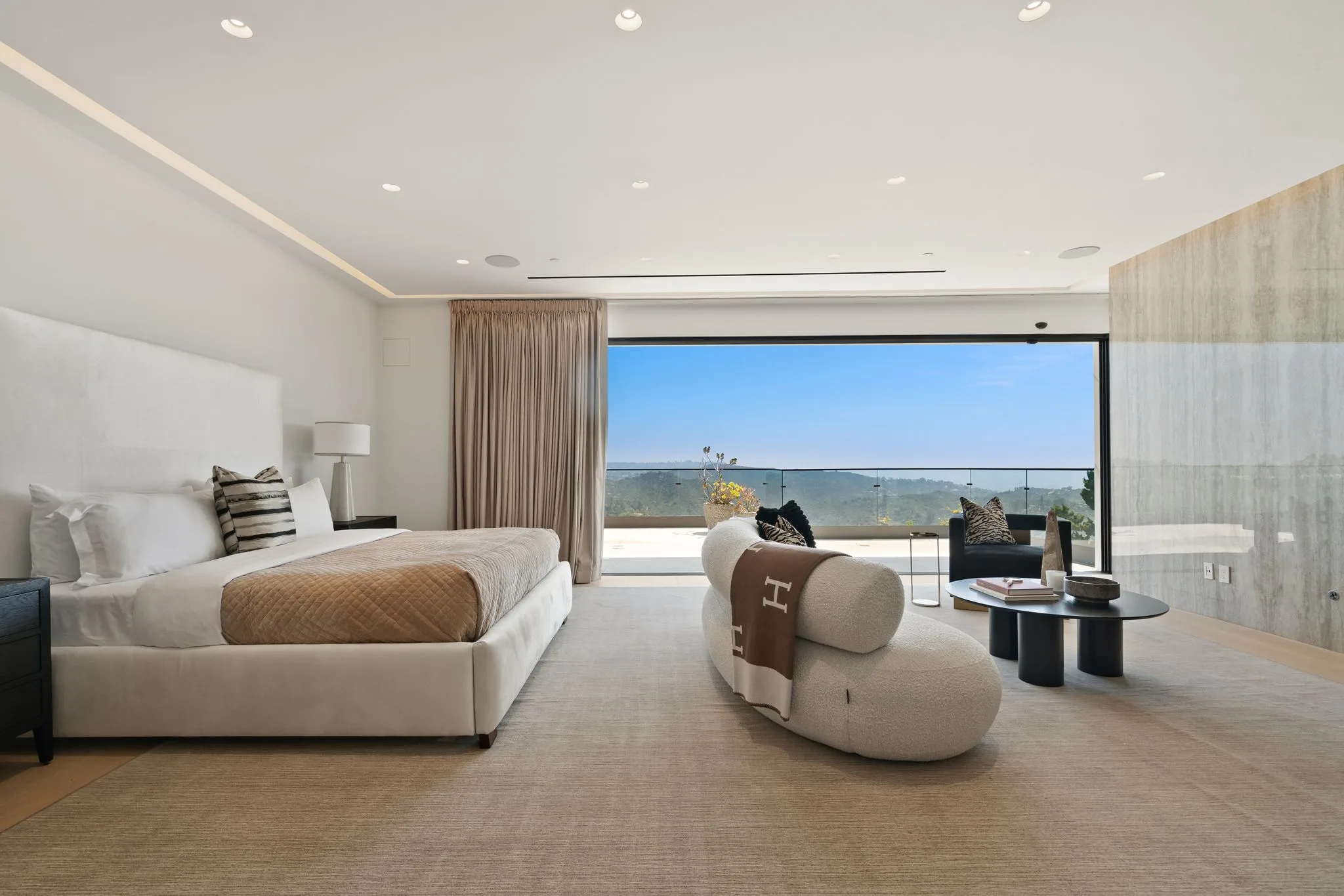 Primary suite with sliding wall open to a private terrace and hazy canyon horizon