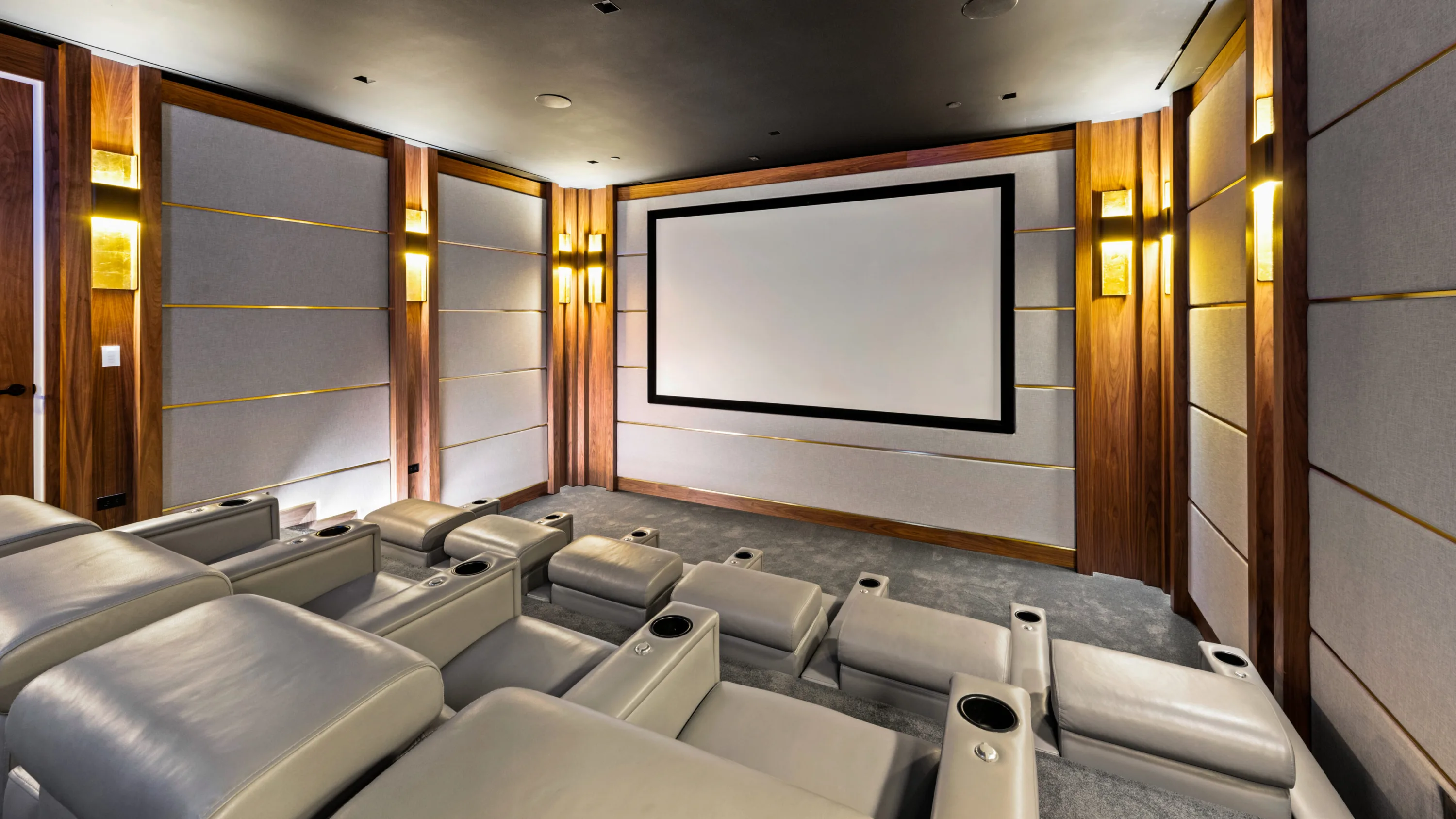 Private theatre with tiered recliners, walnut and fabric acoustic panels and a large projection screen
