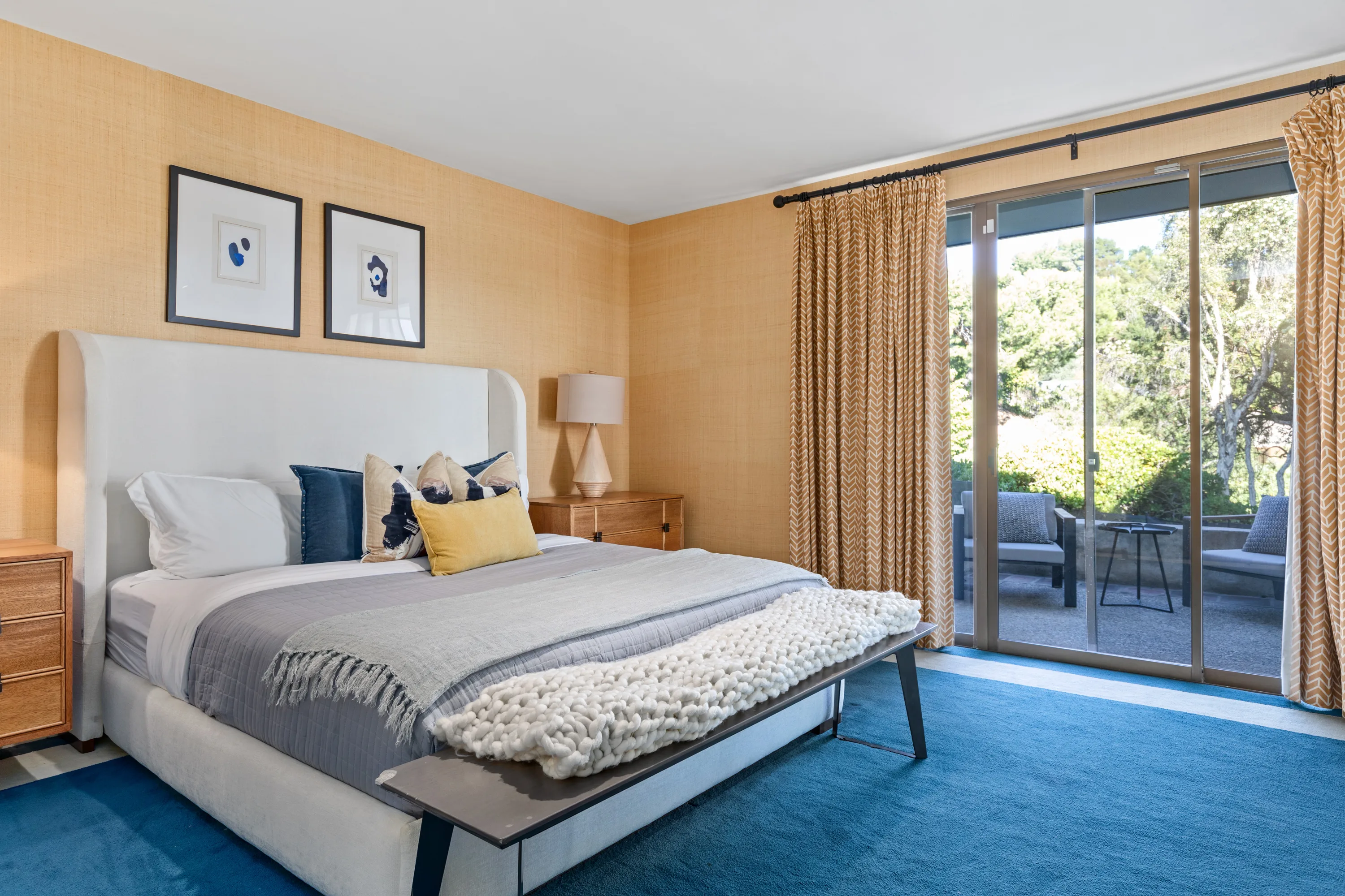 Guest bedroom in grasscloth and blue carpet, sliding doors opening to a private garden terrace