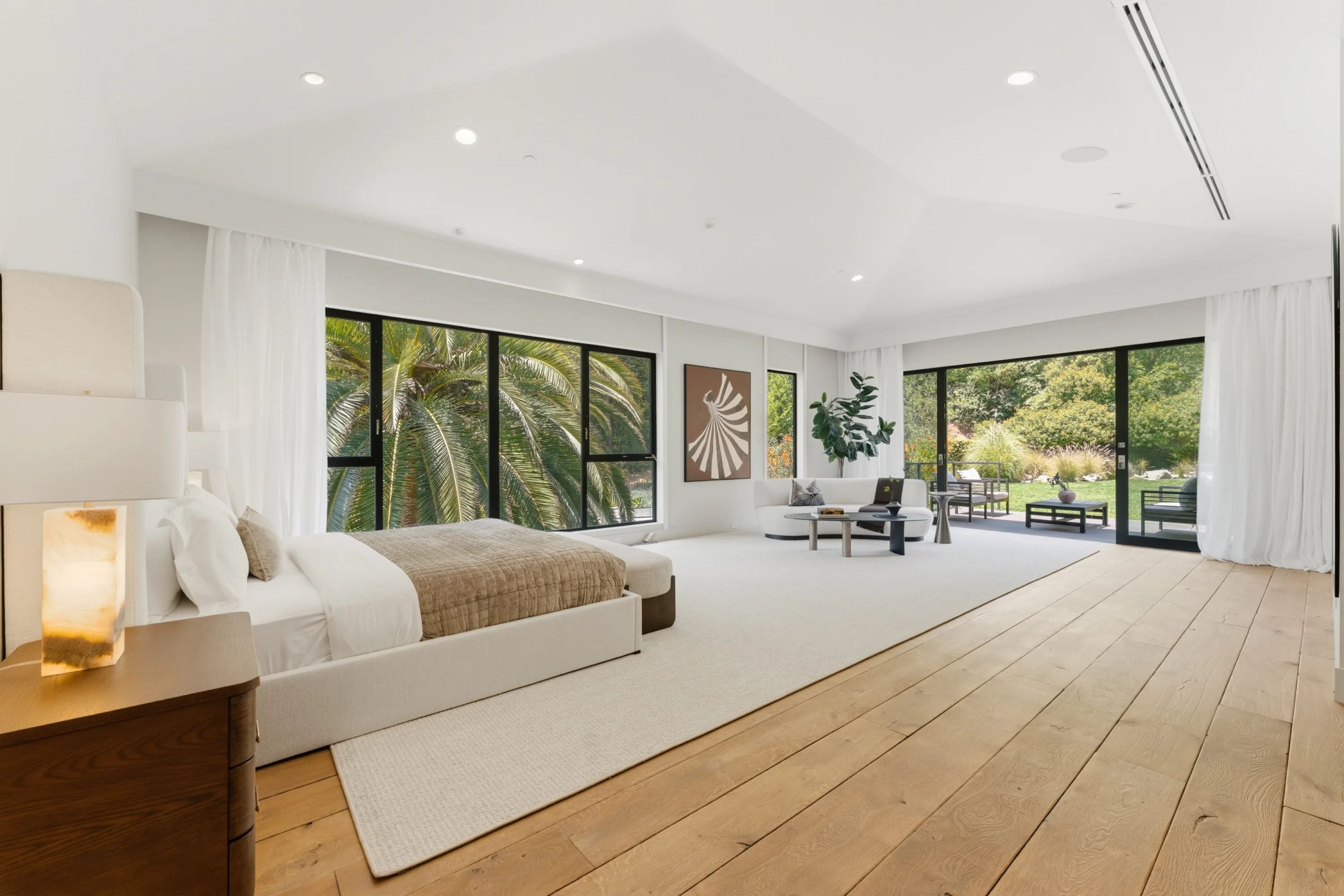 Primary suite under a vaulted ceiling, with sitting area and sliders to a garden terrace