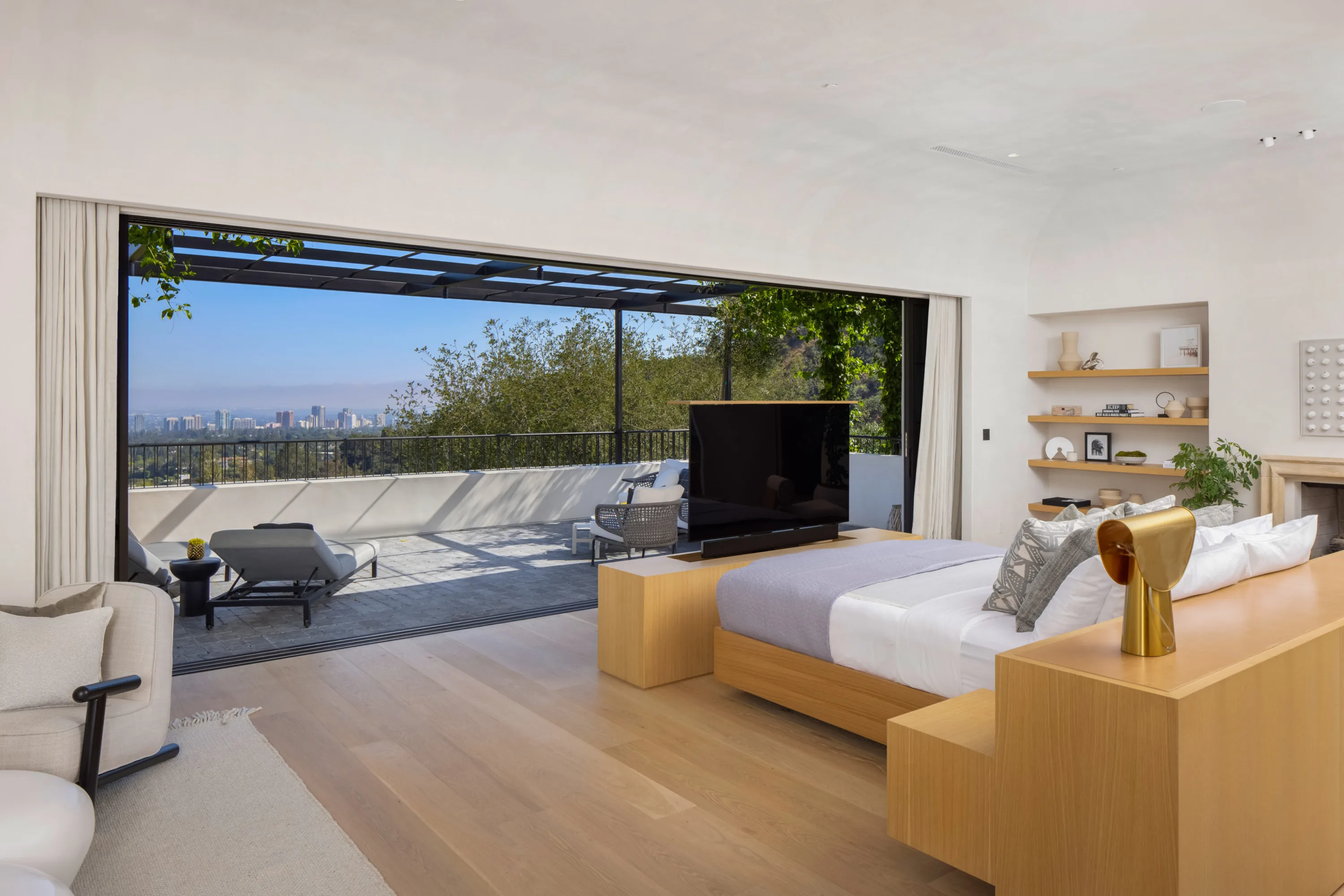 Primary suite with sliding walls open to a terrace and skyline view over the treetops