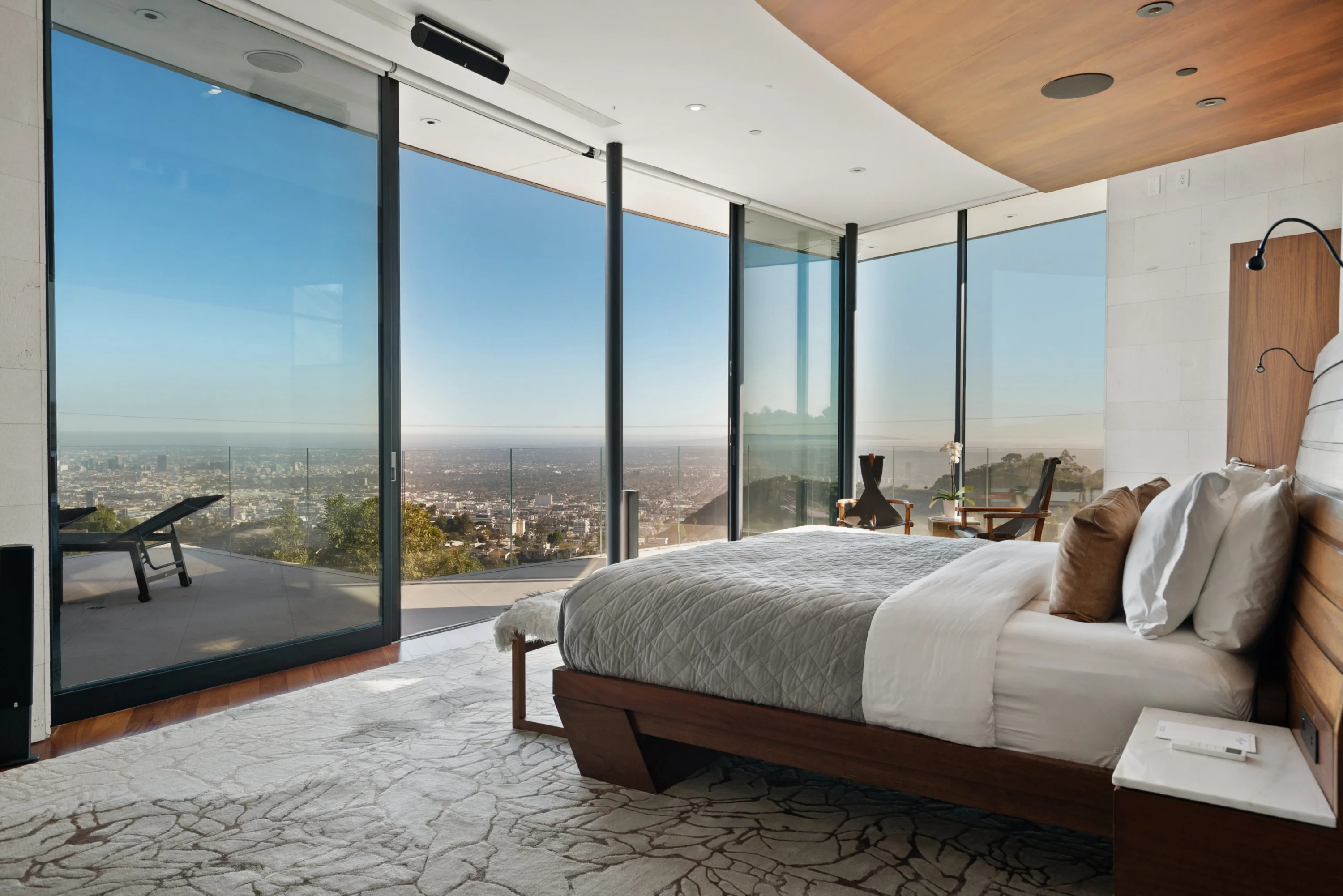 Bedroom corner glazed on two sides, sun lounger on the balcony and the basin of the city below
