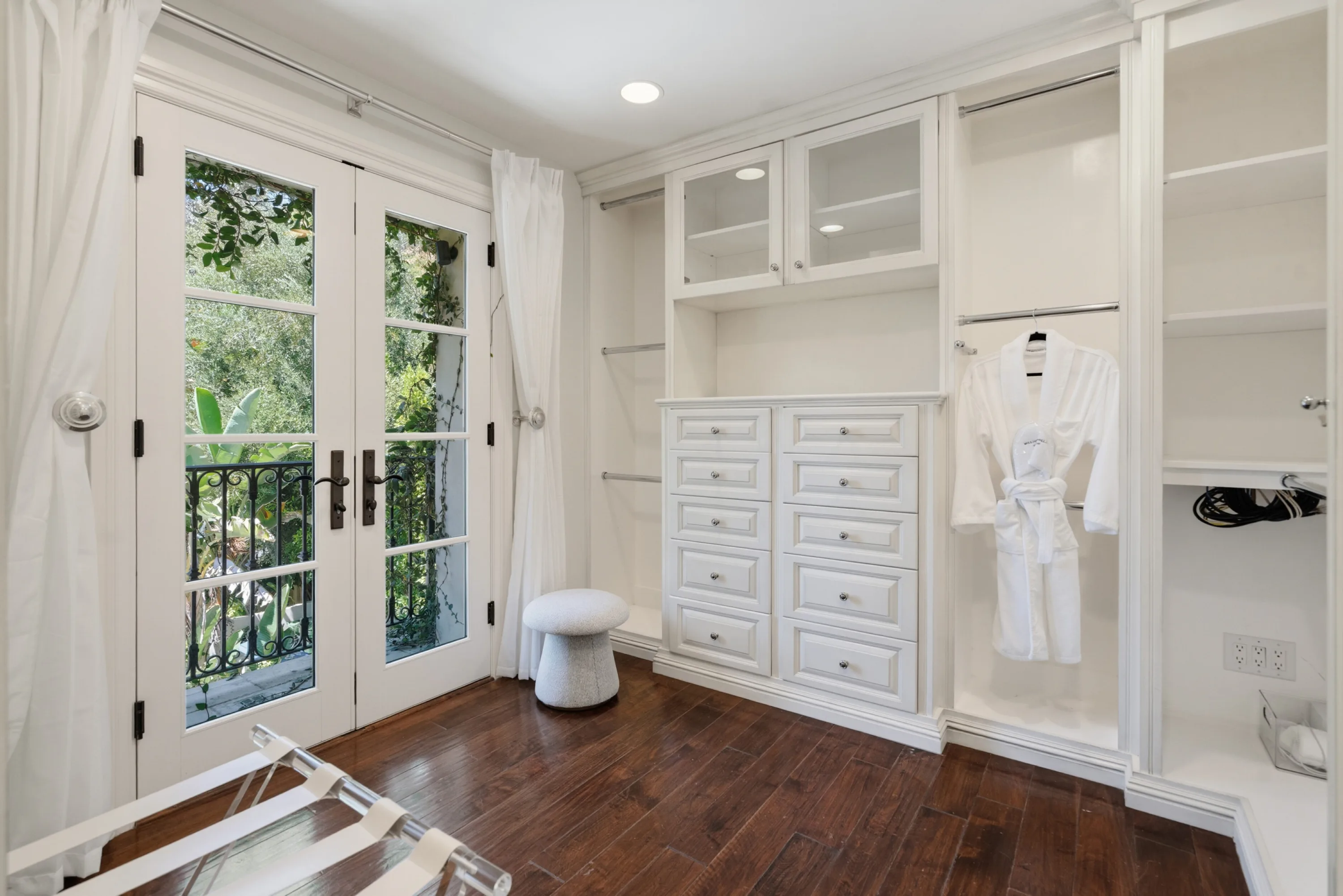 Fitted dressing room with built-in drawers, hanging robe and French doors to a leafy balcony
