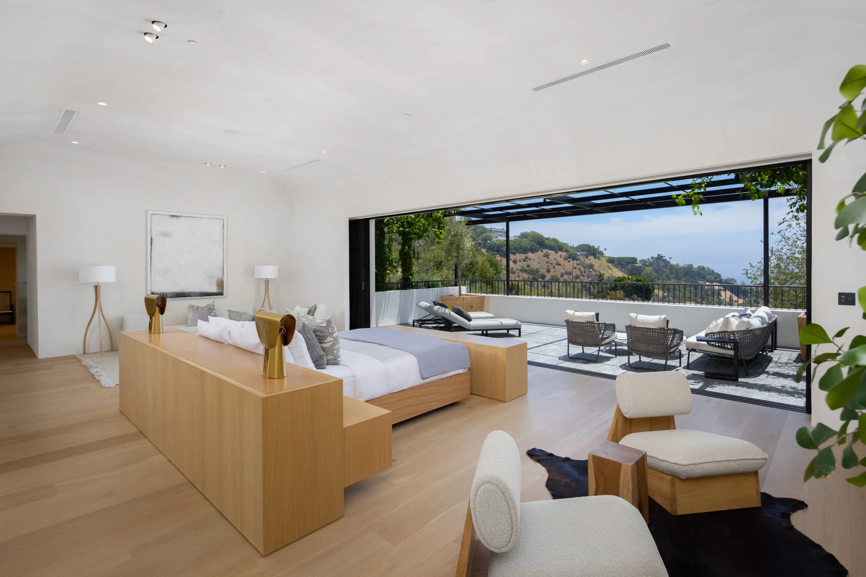 Oak-panelled bedroom opening full-width onto a canyon-facing balcony with lounge seating