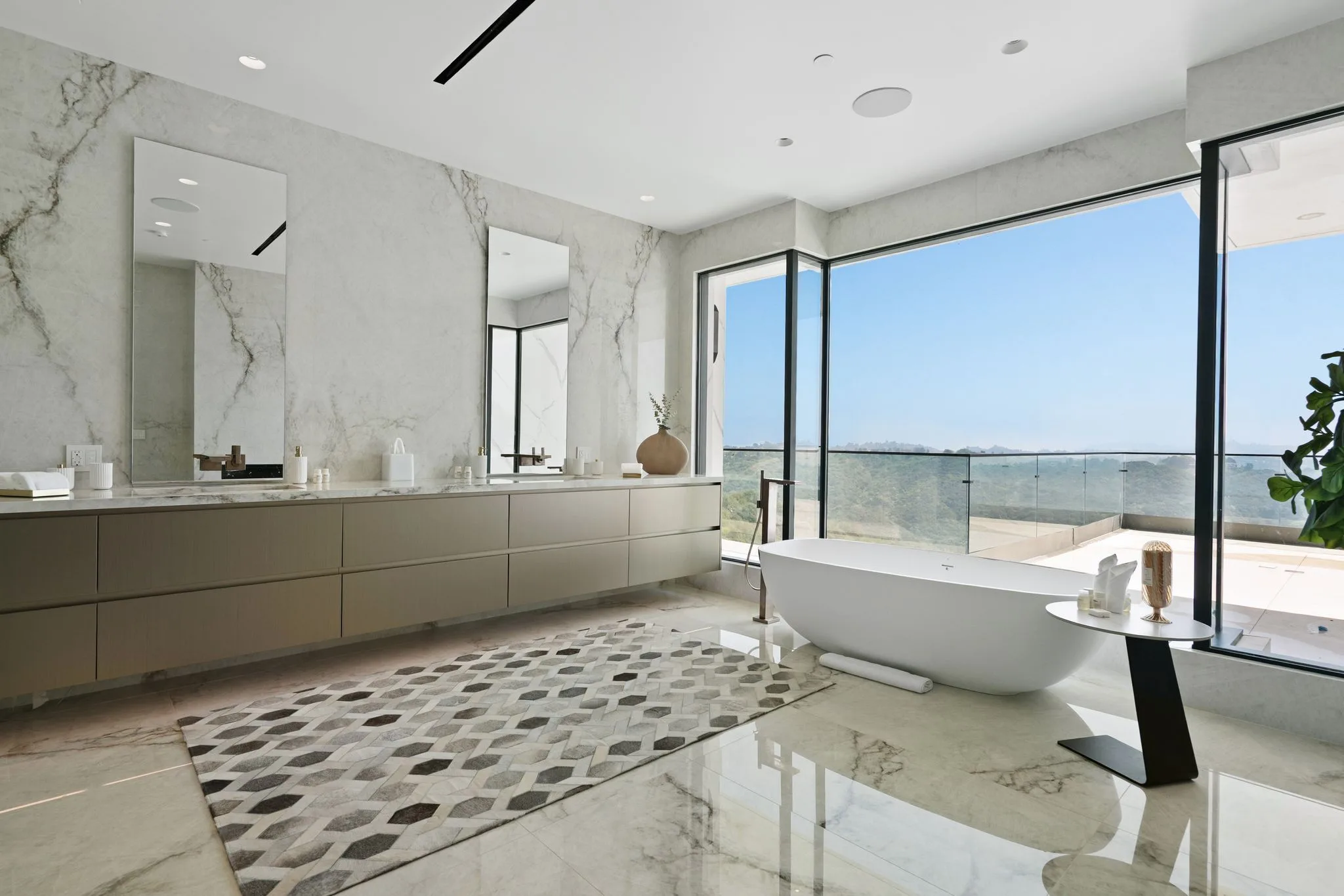 Marble primary bathroom with long double vanity and freestanding tub beside the terrace glazing