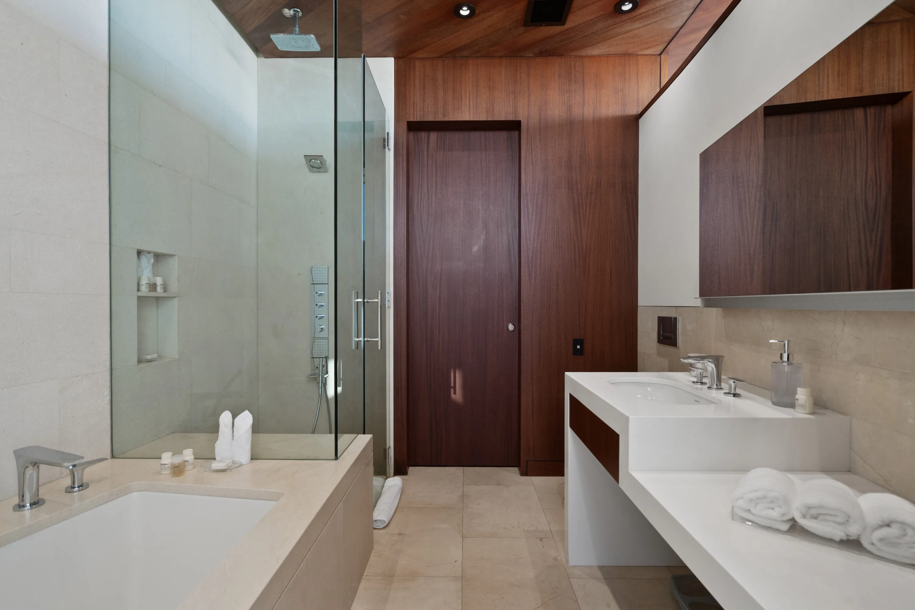 Ensuite with walk-in rain shower behind glass, soaking tub and a long white double vanity