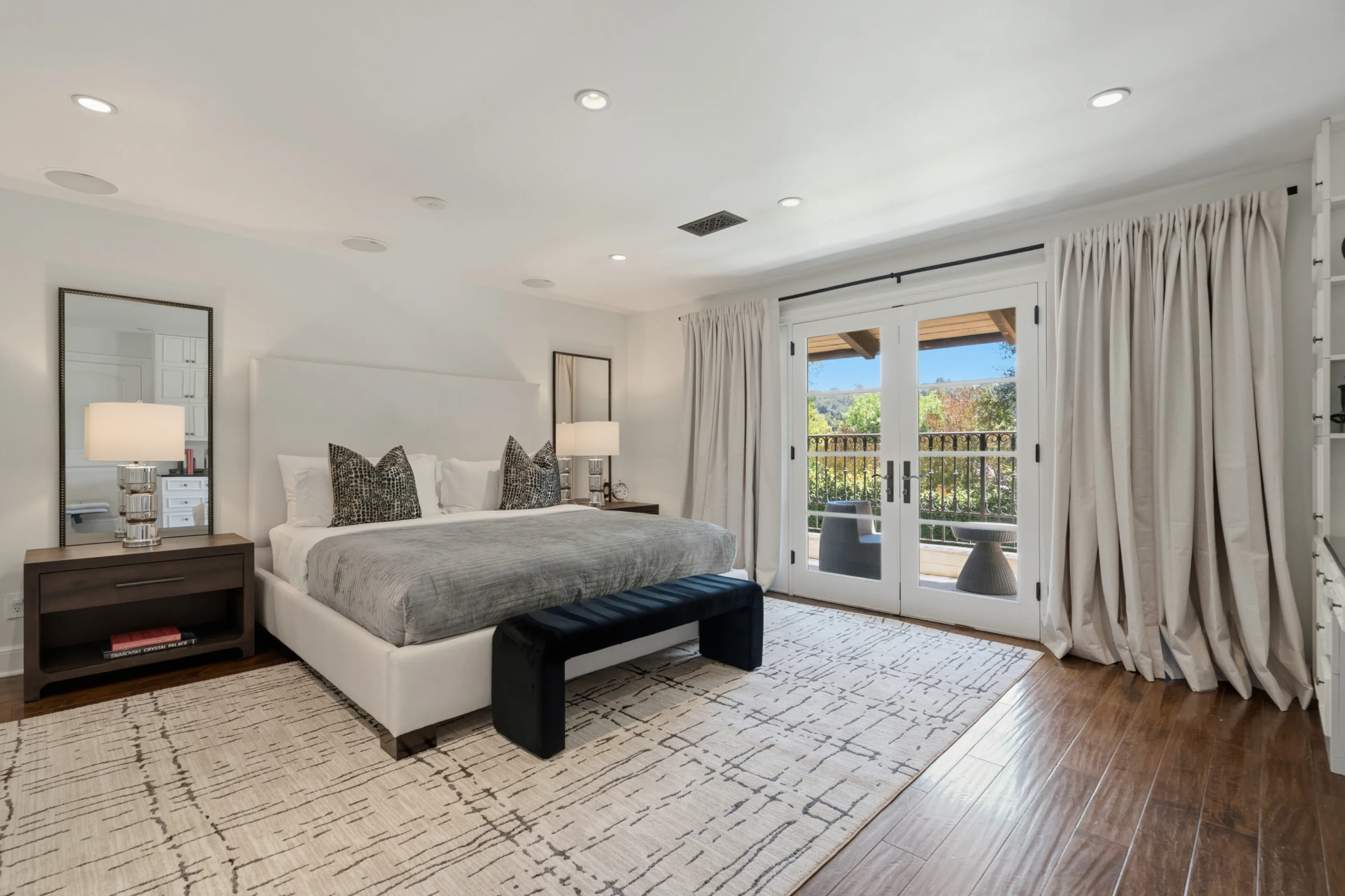 Guest bedroom with king bed, patterned rug and French doors to a covered balcony with canyon outlook