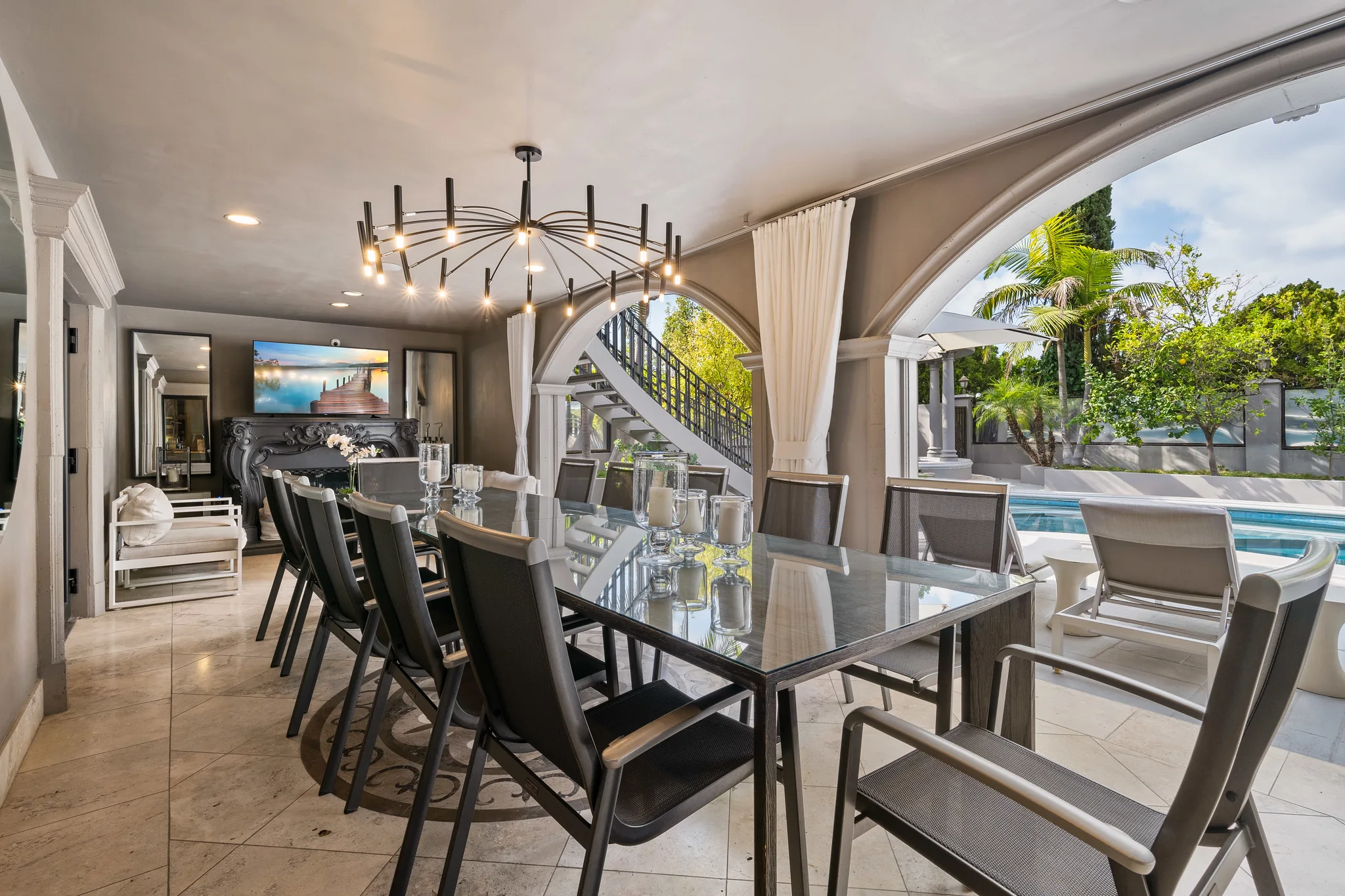 Covered poolside dining loggia seating ten, with sputnik chandelier and arches opening straight onto the water
