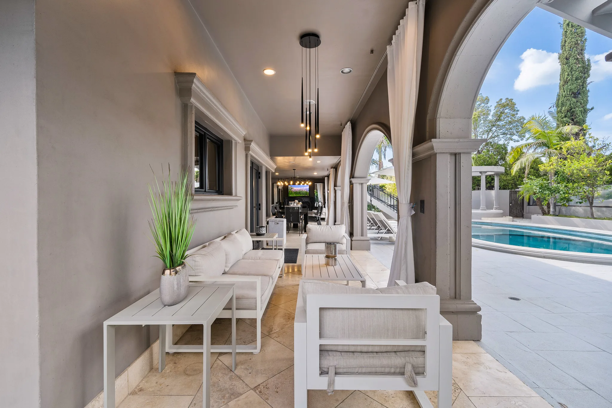 Arched loggia running the length of the house, lined with white sofas and looking out to the turquoise pool