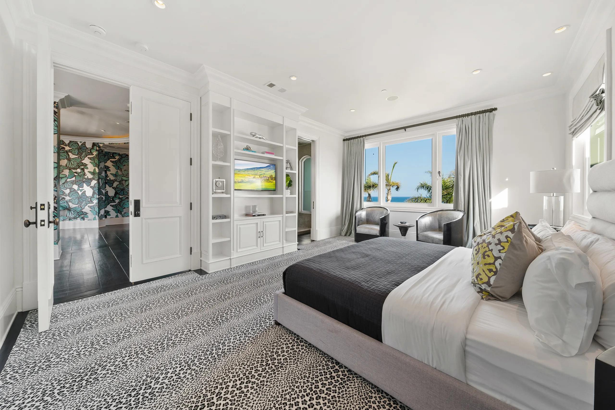 Bright guest suite with leopard-print carpet, built-in media wall and window seating over the water