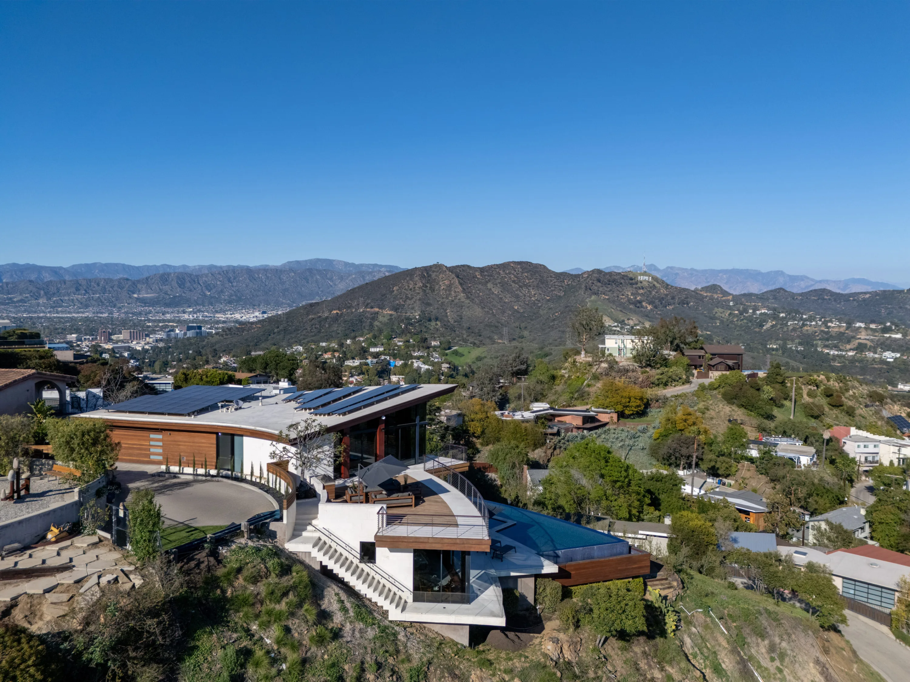 Aerial of the hillside estate, its cantilevered pool deck facing the canyon and distant Hollywood sign