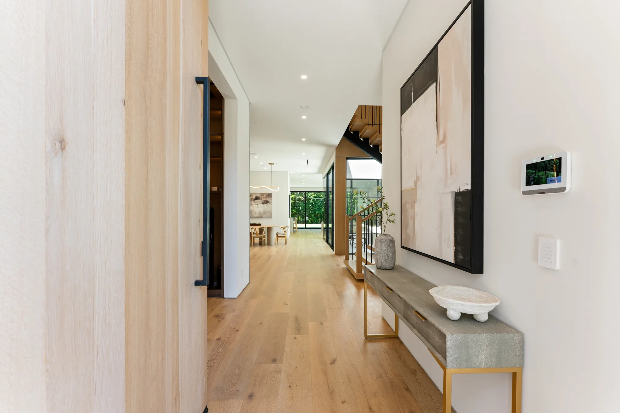 Entry hall with oak floors, shagreen console and large abstract canvas leading toward the dining area