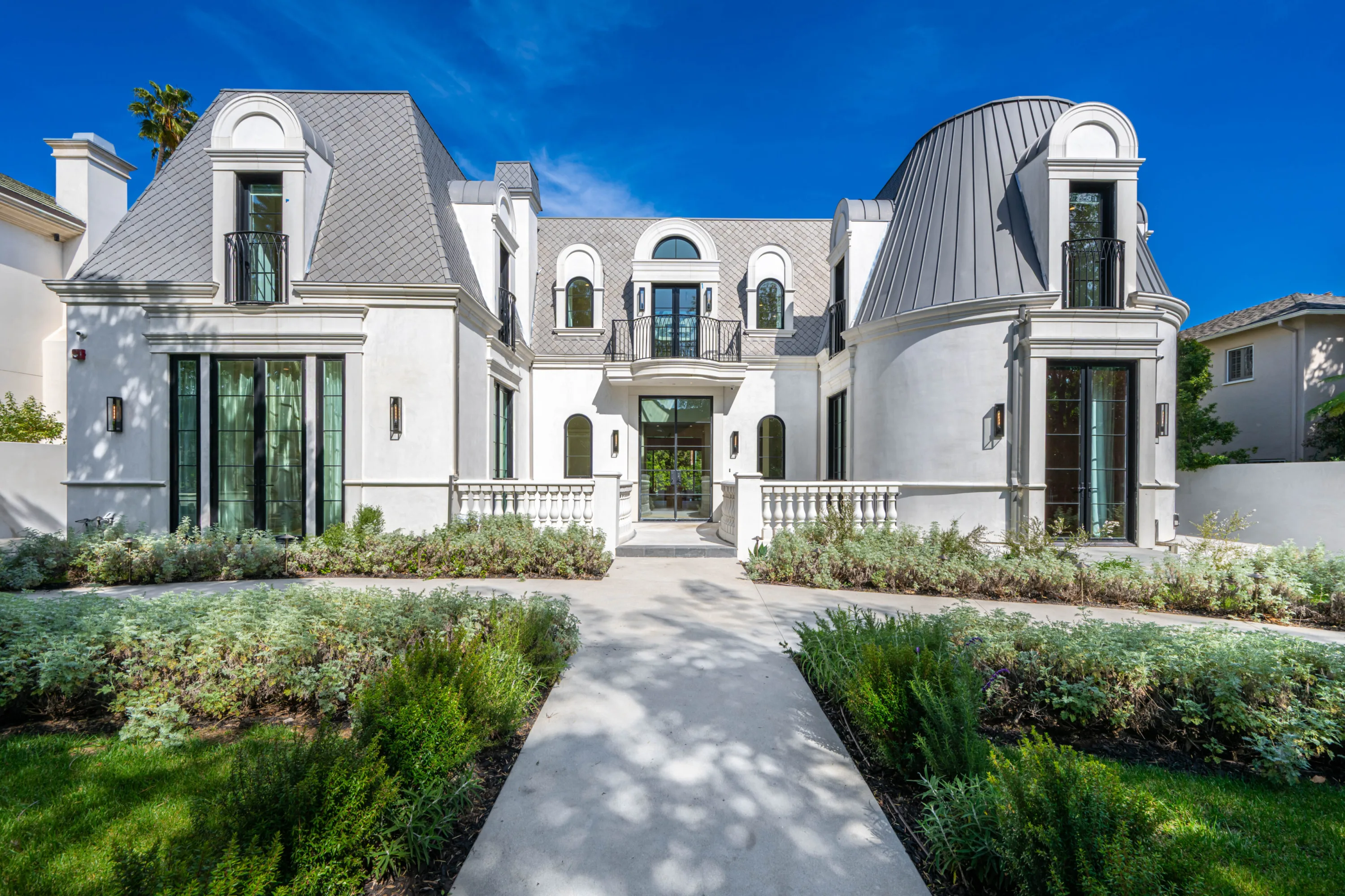 Front elevation of the French-inspired Beverly Hills estate, with slate mansard roof, turret and balustraded entry walk