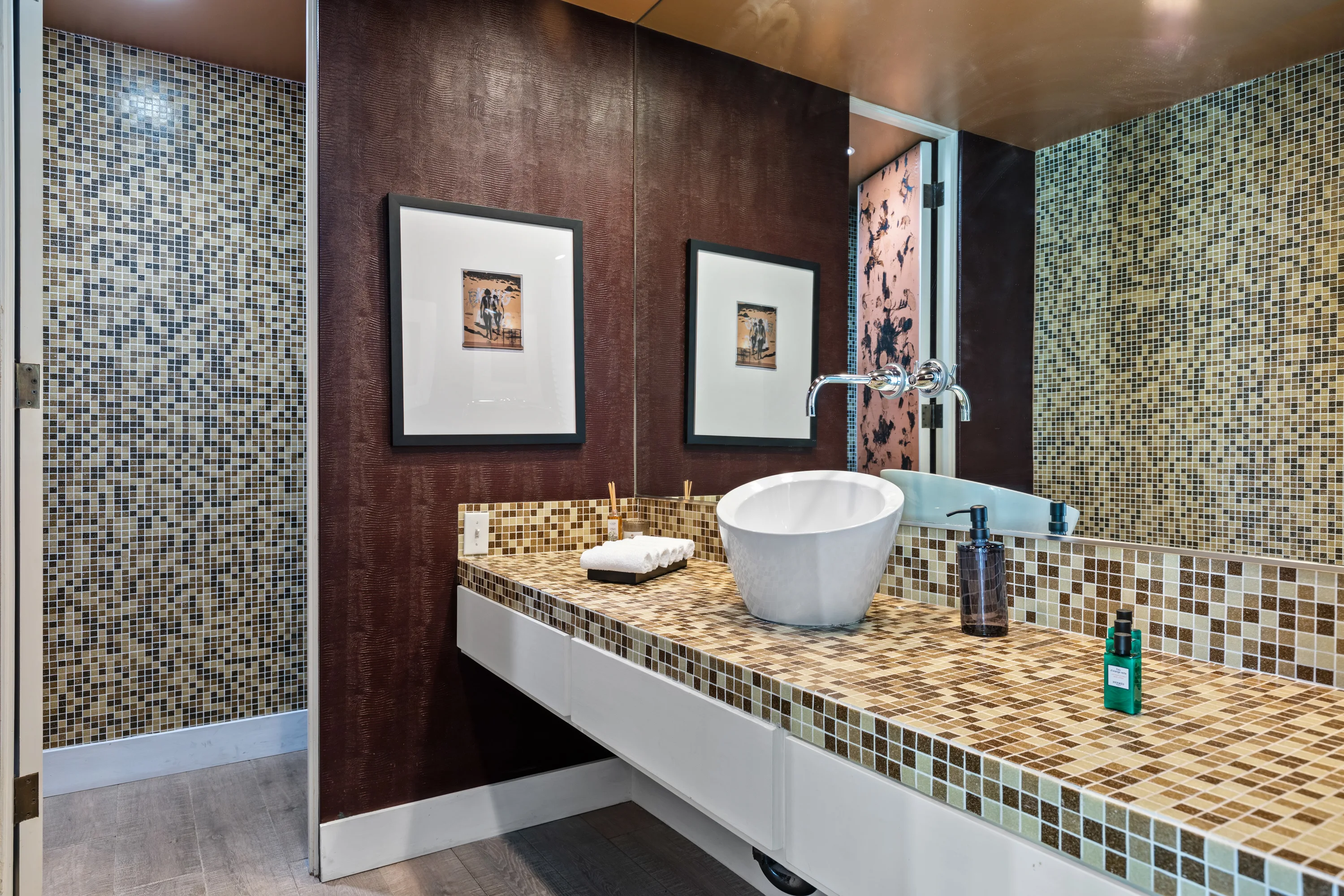 Powder room clad in mosaic tile with vessel basin and wall-mounted chrome tap