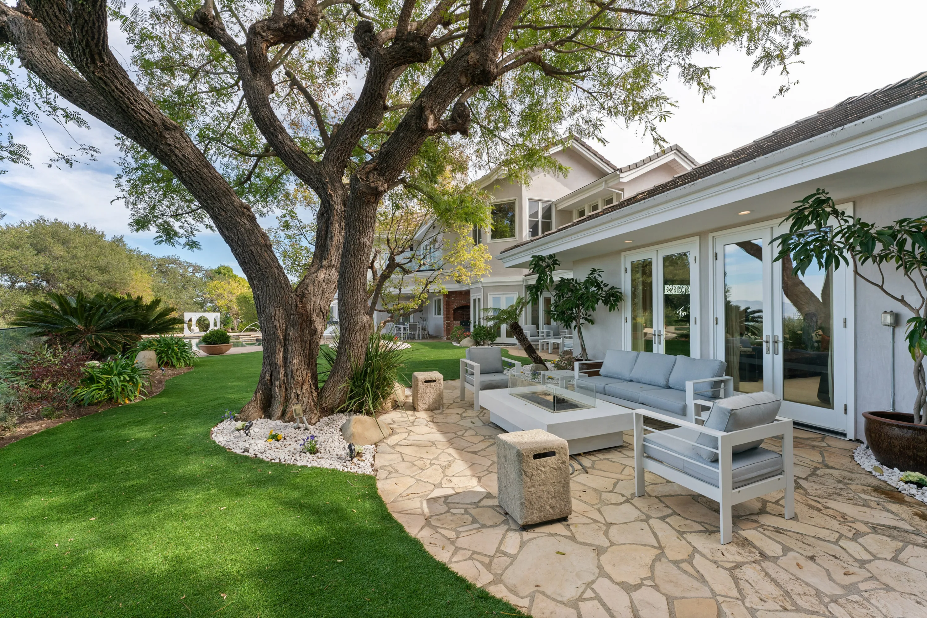 Flagstone terrace with fire table and pale blue sofas beside the lawn and French doors