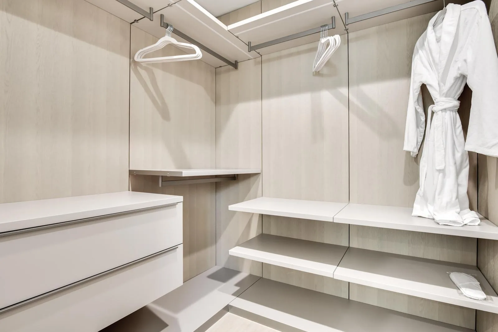Fitted walk-in closet in pale oak with hanging rails, open shelves, drawers and a folded robe