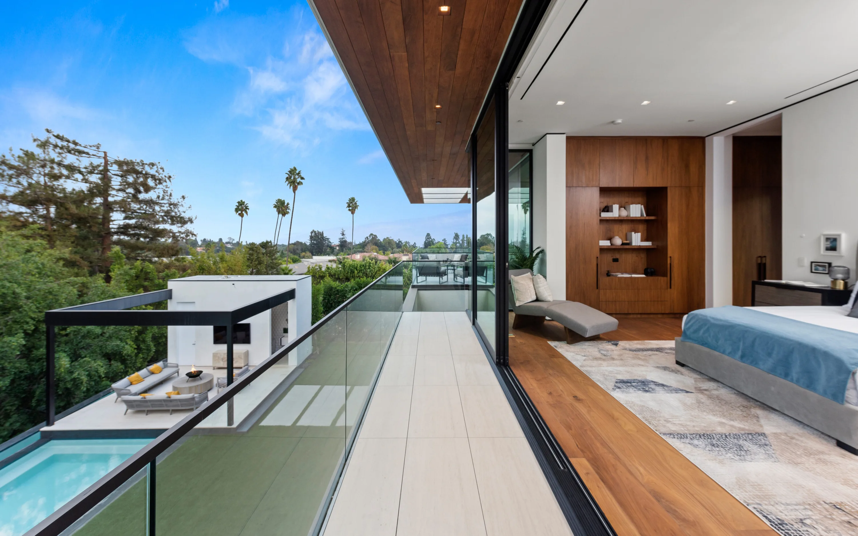 Wraparound balcony off a bedroom, pool and treetops below under a timber soffit