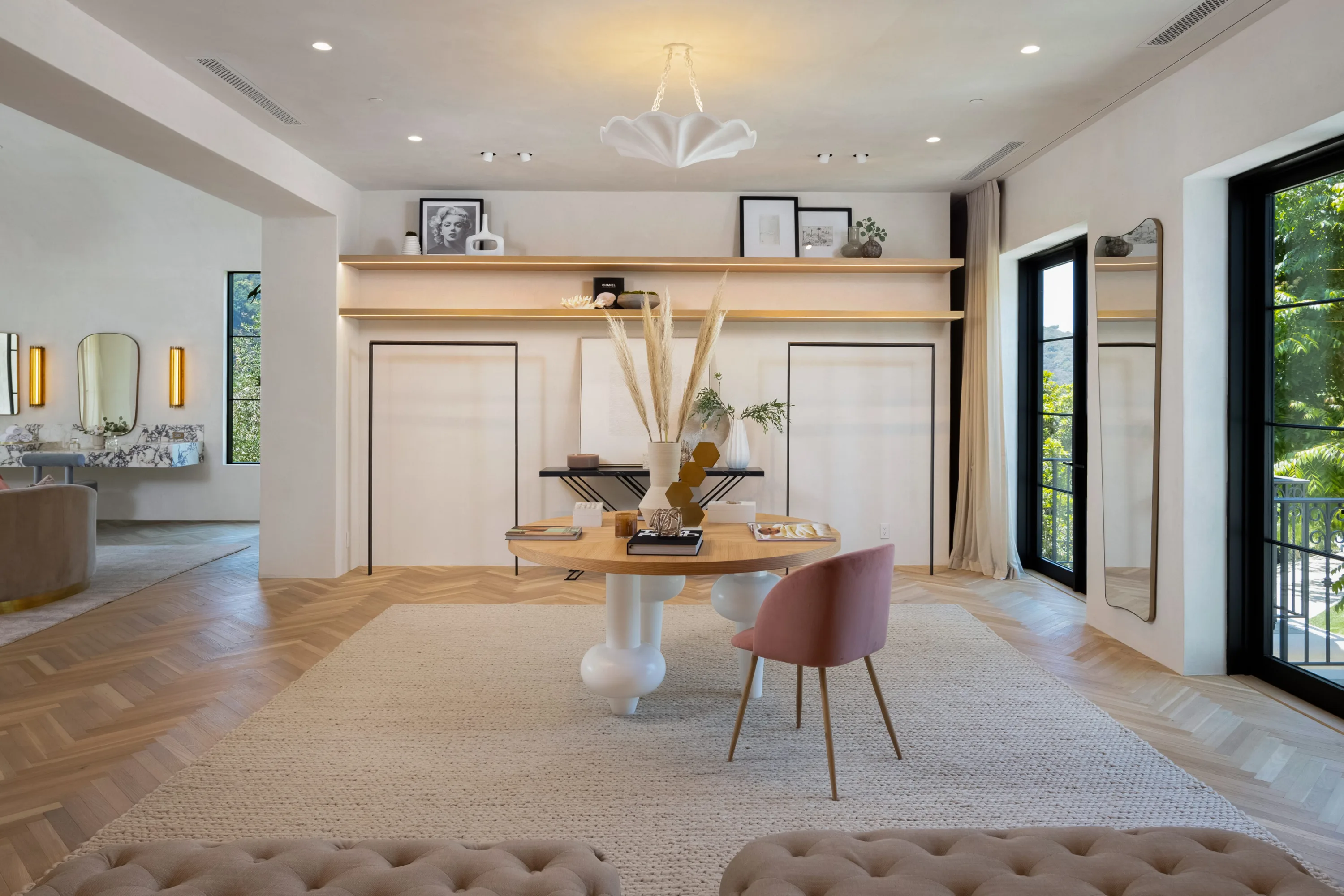 Dressing lounge with round oak table, lit display shelves and balcony doors to the treetops