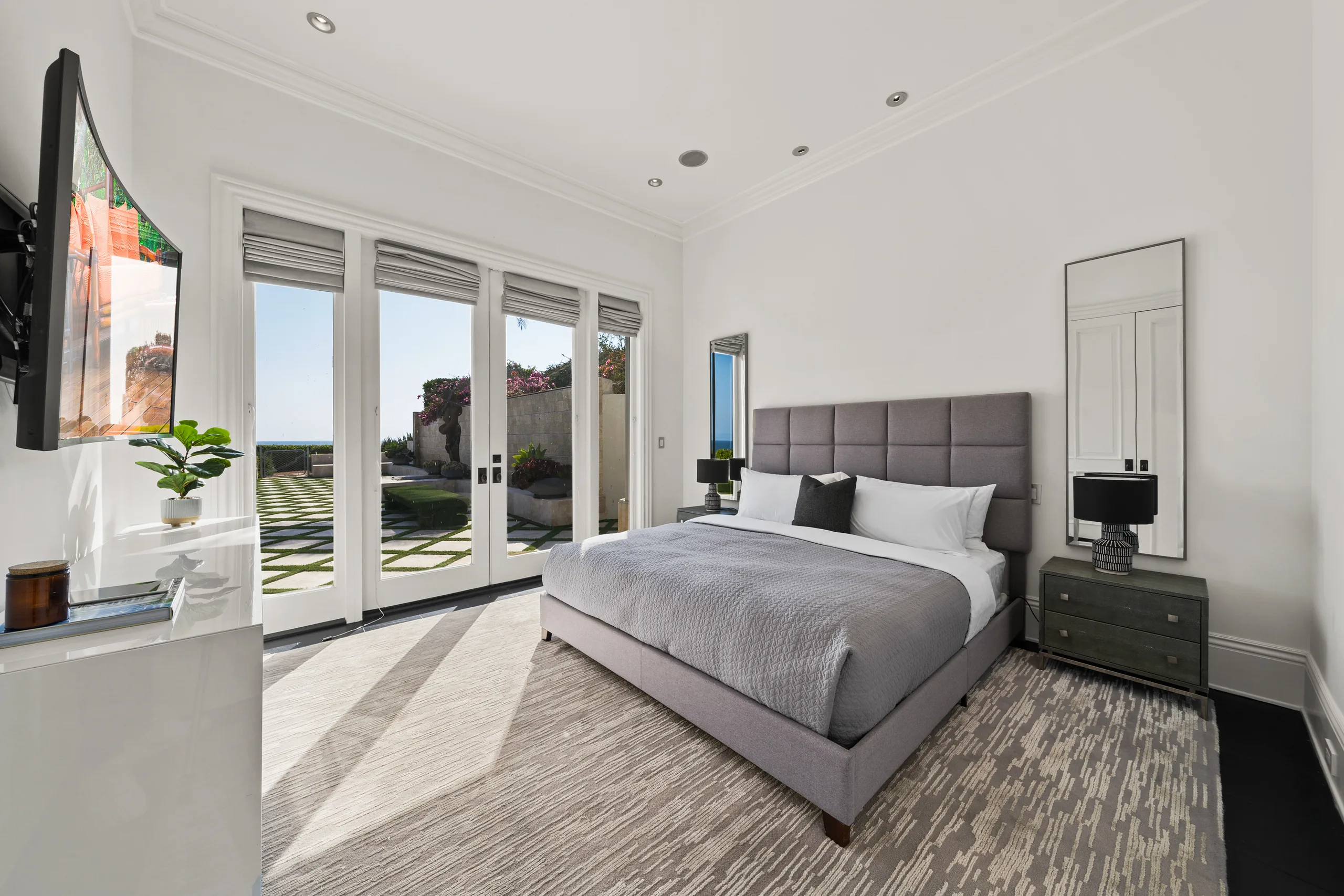 Calm grey guest bedroom with French doors onto the chequerboard lawn and bougainvillea wall