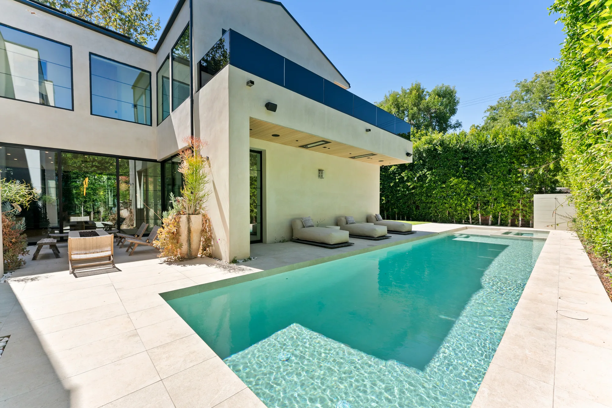 Turquoise lap pool running the length of the house, with daybeds under the cantilevered terrace