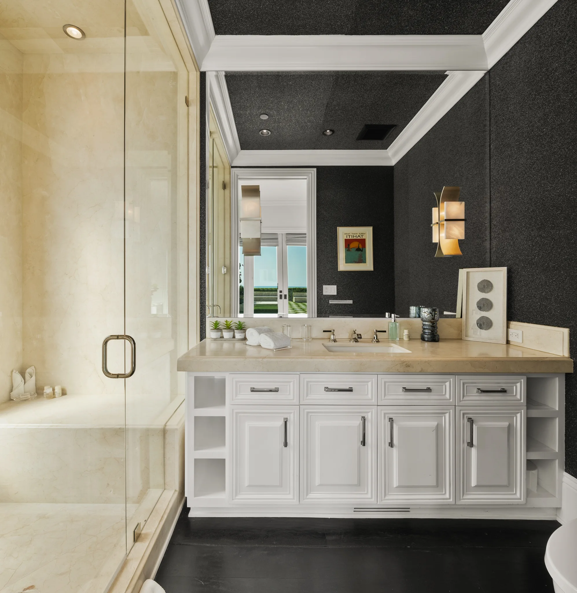 Guest bath with limestone vanity, glass shower and black glitter walls; framed poster reads "ITIHAT"