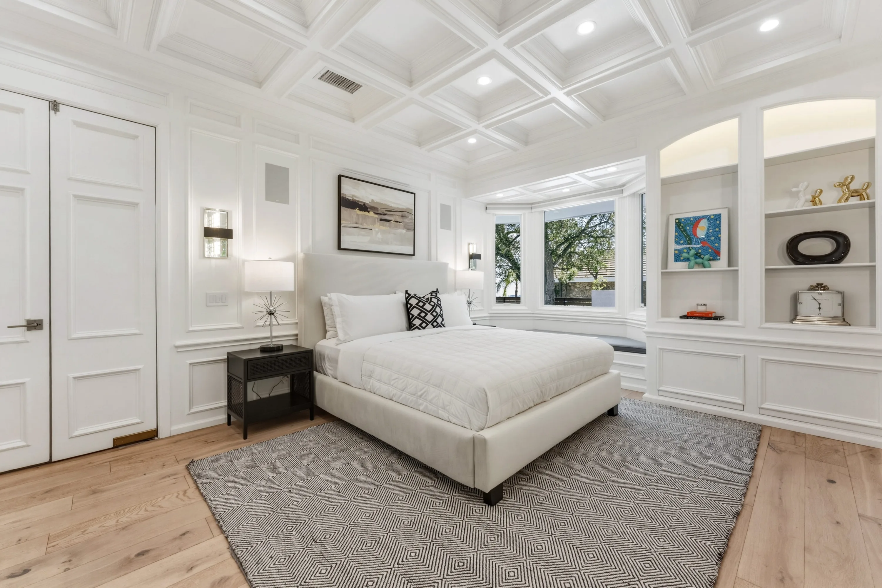 King bedroom panelled in white with coffered ceiling, window bay and display niches