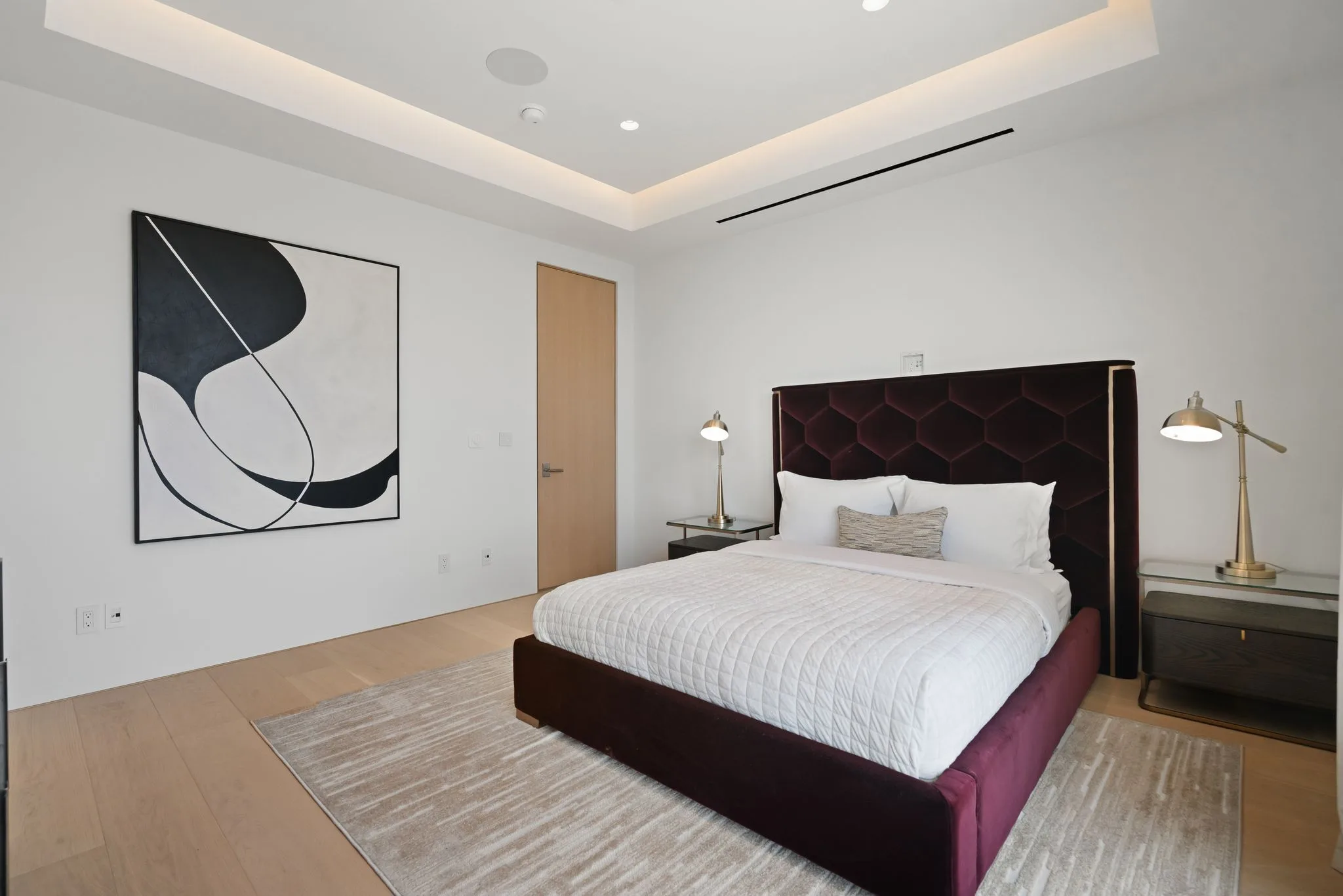 King bedroom anchored by an oxblood honeycomb-tufted headboard and bold black-and-white artwork