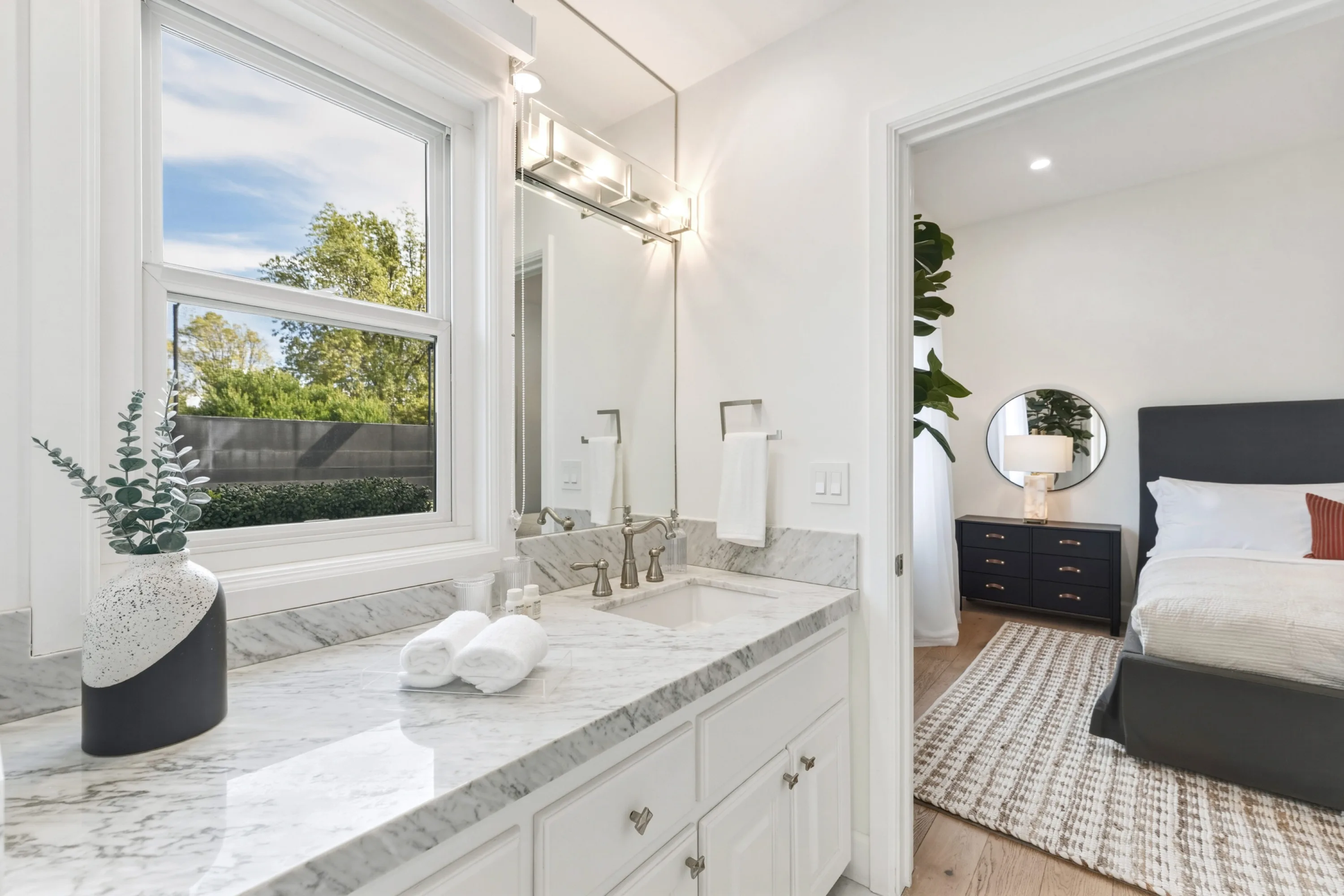 Marble-topped ensuite vanity with garden window, opening through to the adjoining guest bedroom
