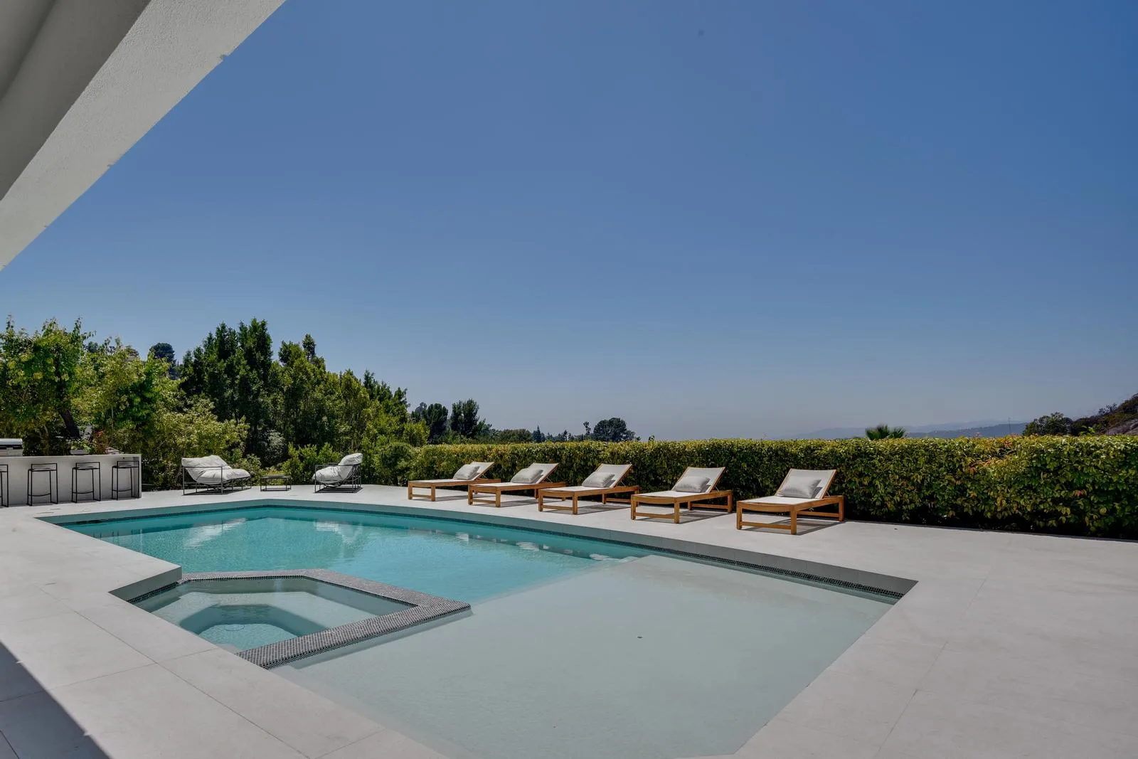 Private pool with sunken spa, teak loungers and a hedged horizon opening to distant hills