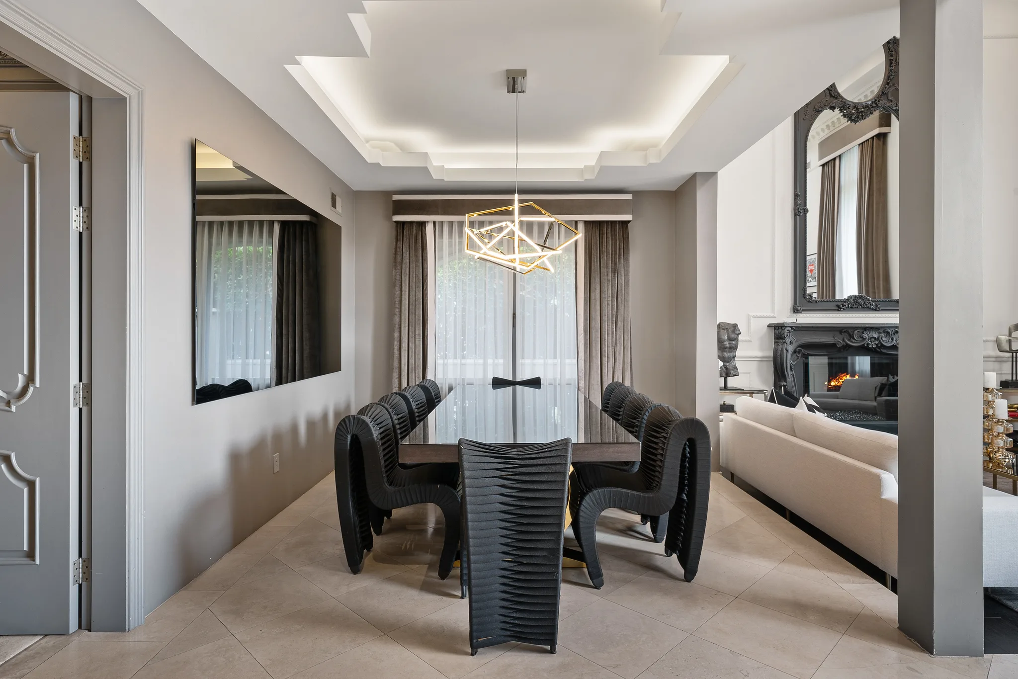 Formal dining room seating eight, with pleated black chairs under a gold geometric pendant