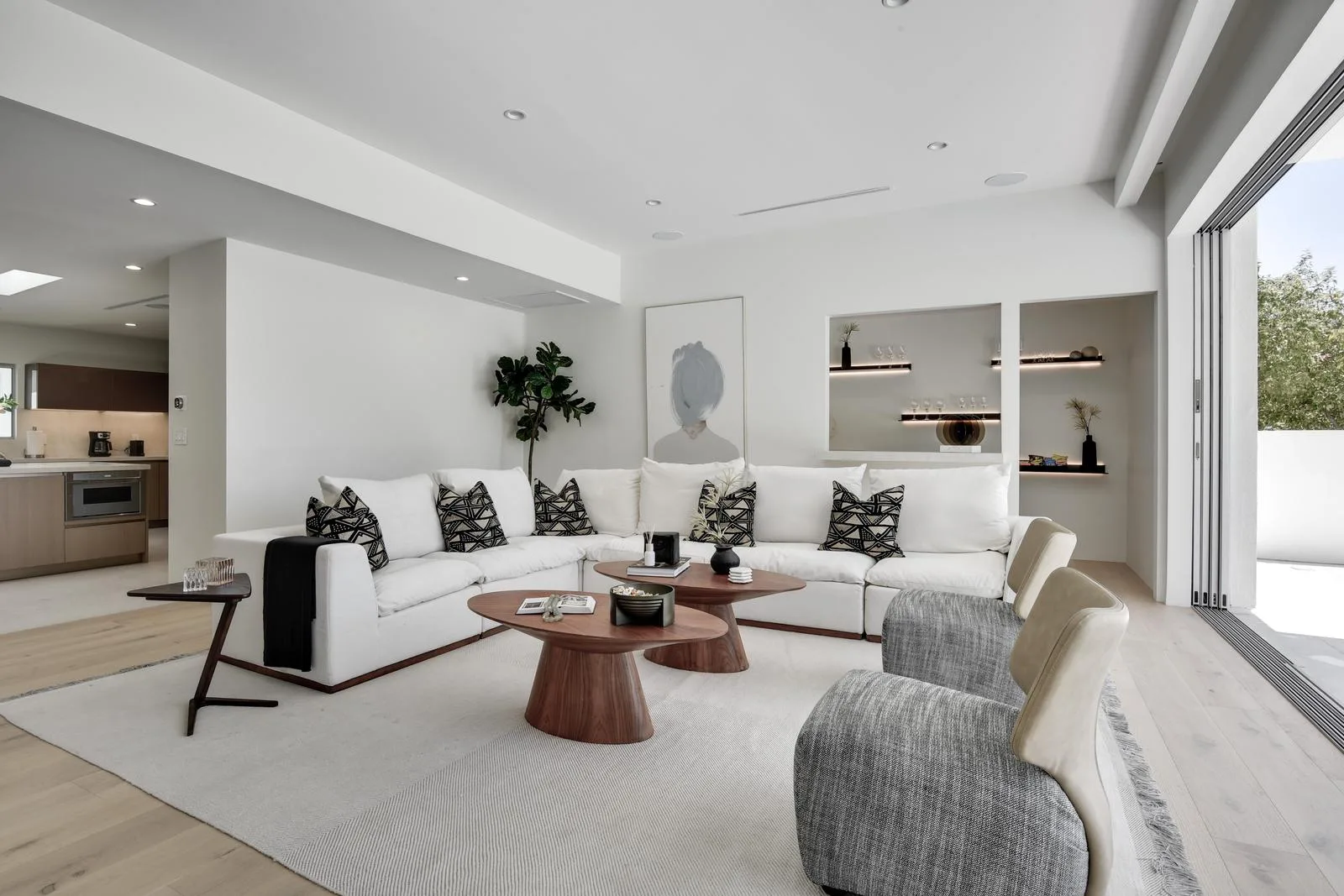 Family room sectional beside lit display niches, with the kitchen visible through the open plan