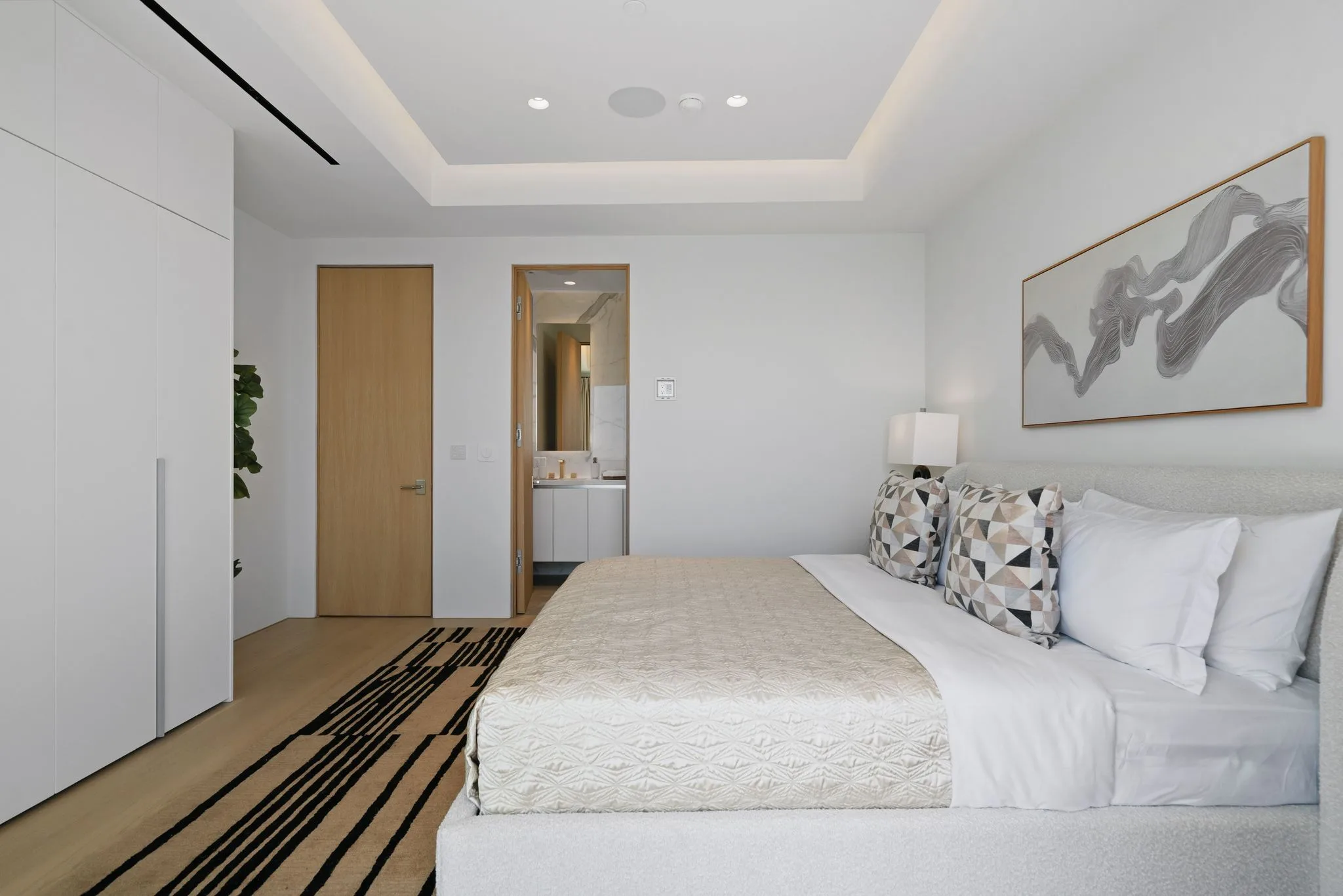 Guest bedroom looking through to its marble ensuite, with concealed closets and striped wool rug