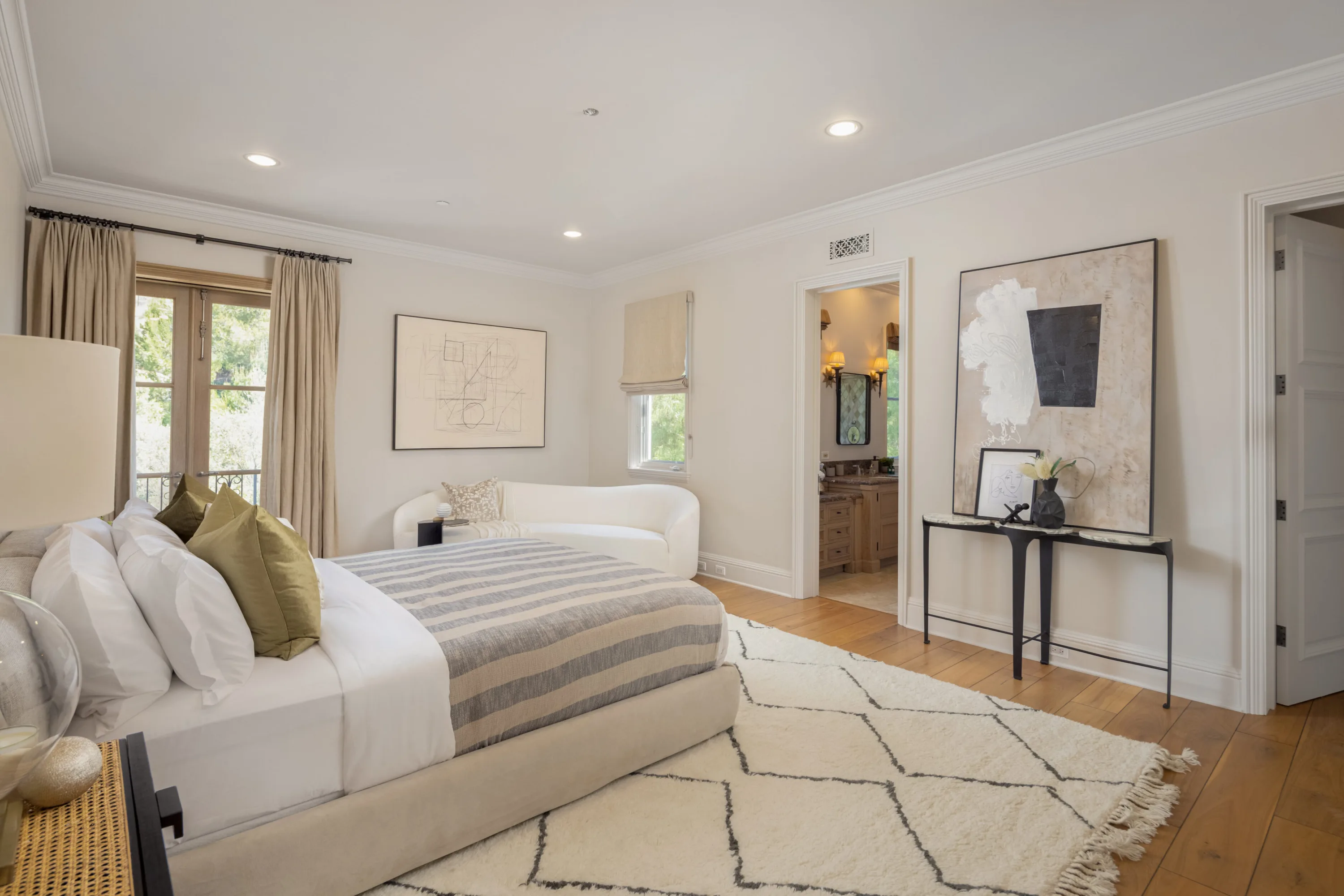 Guest room with striped throw, curved chaise and diamond-pattern rug beside the ensuite door
