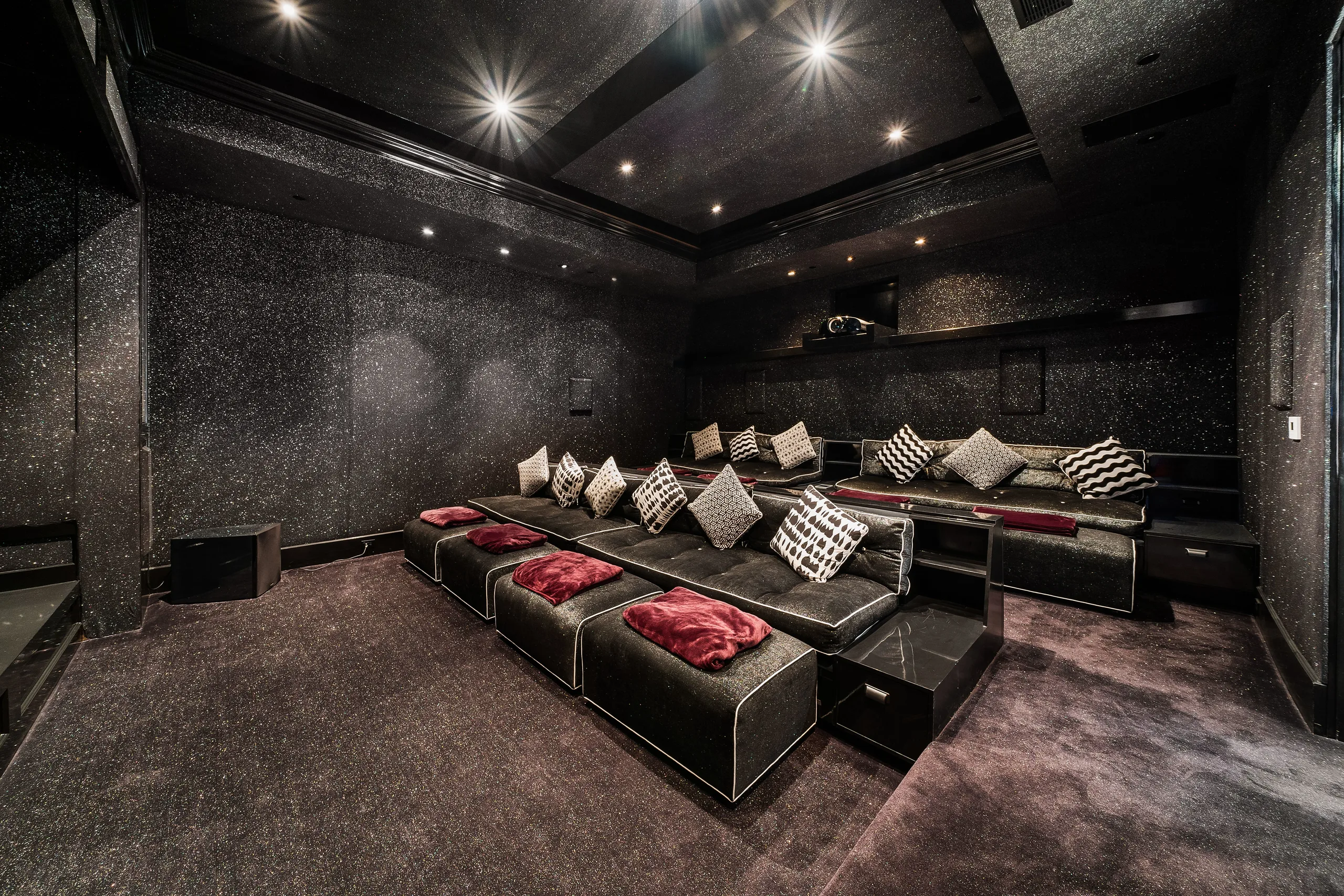 Tiered home cinema in charcoal glitter finish, with plush lounge seating, velvet cushions and crimson throws