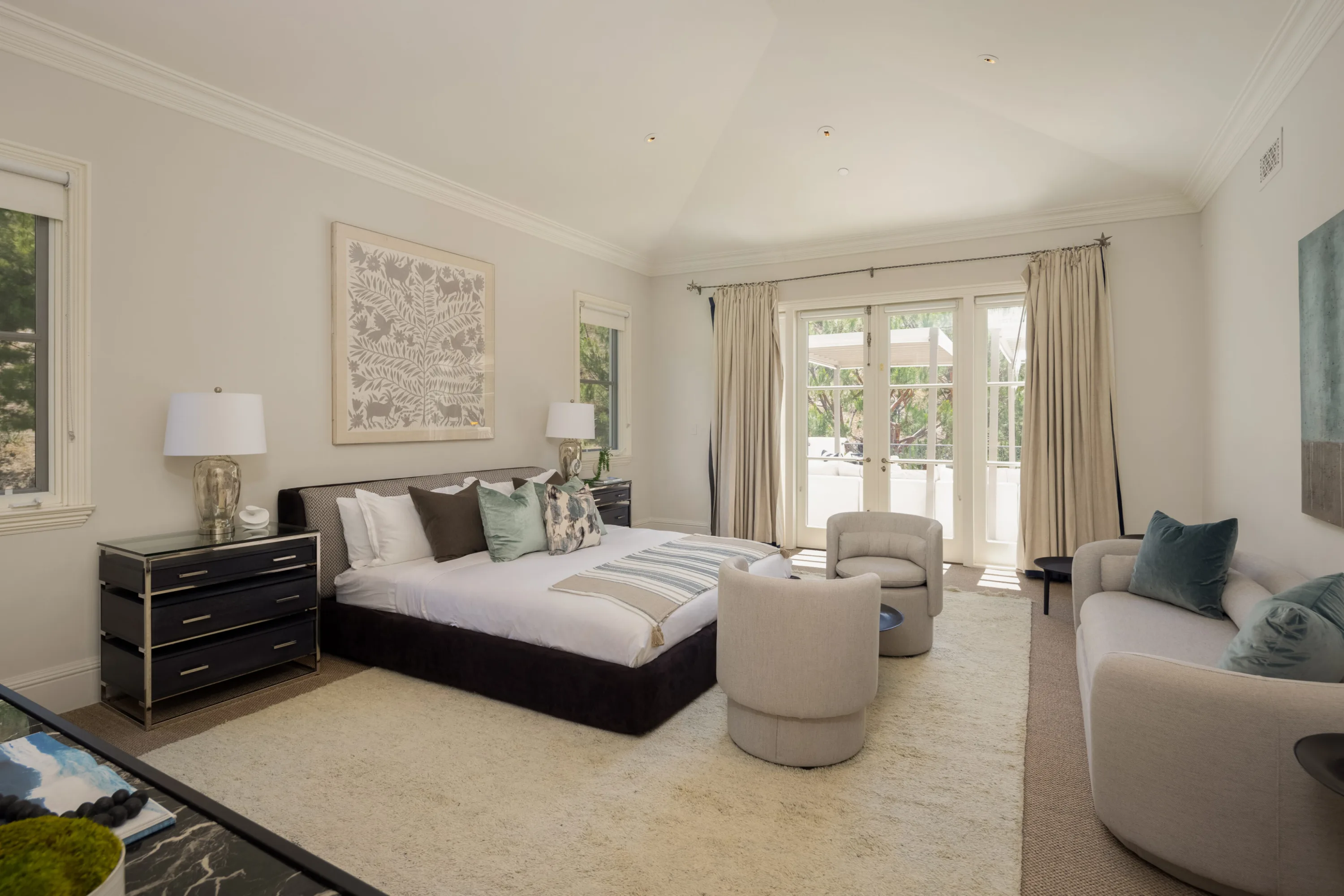 Vaulted guest suite with sitting area, swivel chairs and doors opening to a sunlit terrace