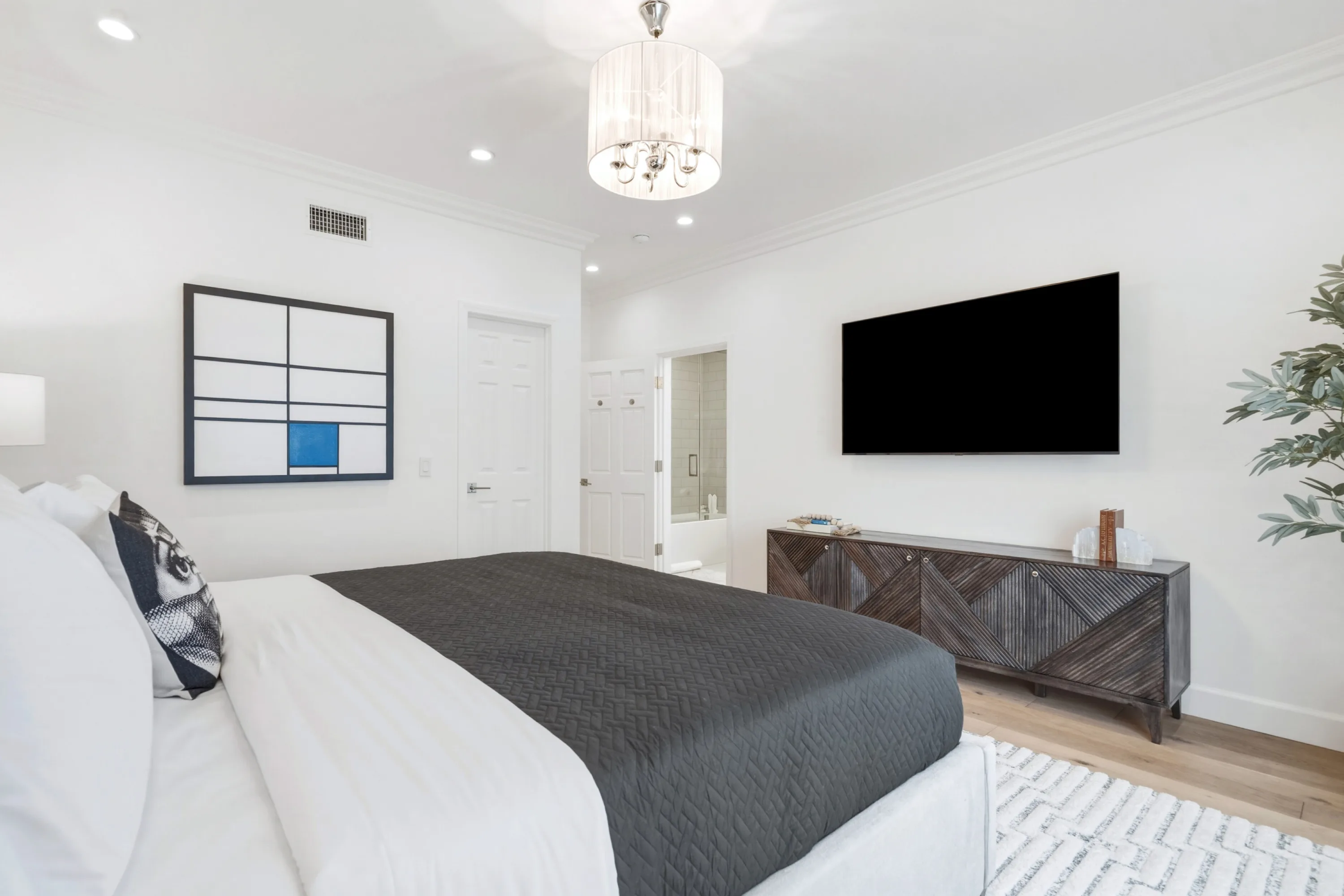 Same bedroom from the pillows, showing carved sideboard, mounted TV and door to the ensuite