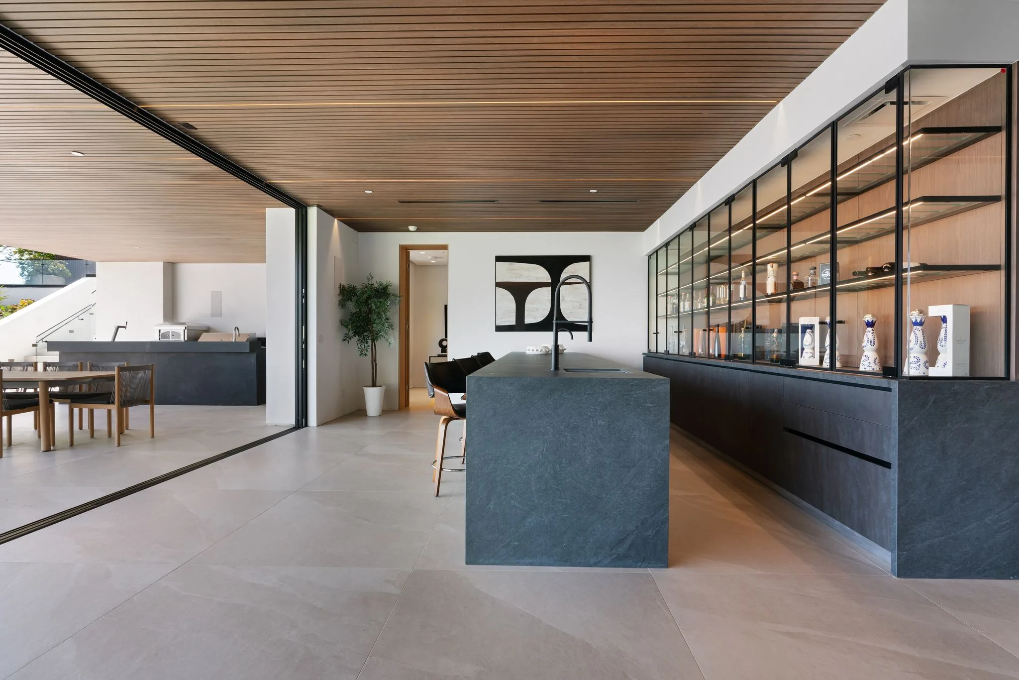 Prep island in dark stone beside glass display cabinetry, dining area and pocketing doors beyond
