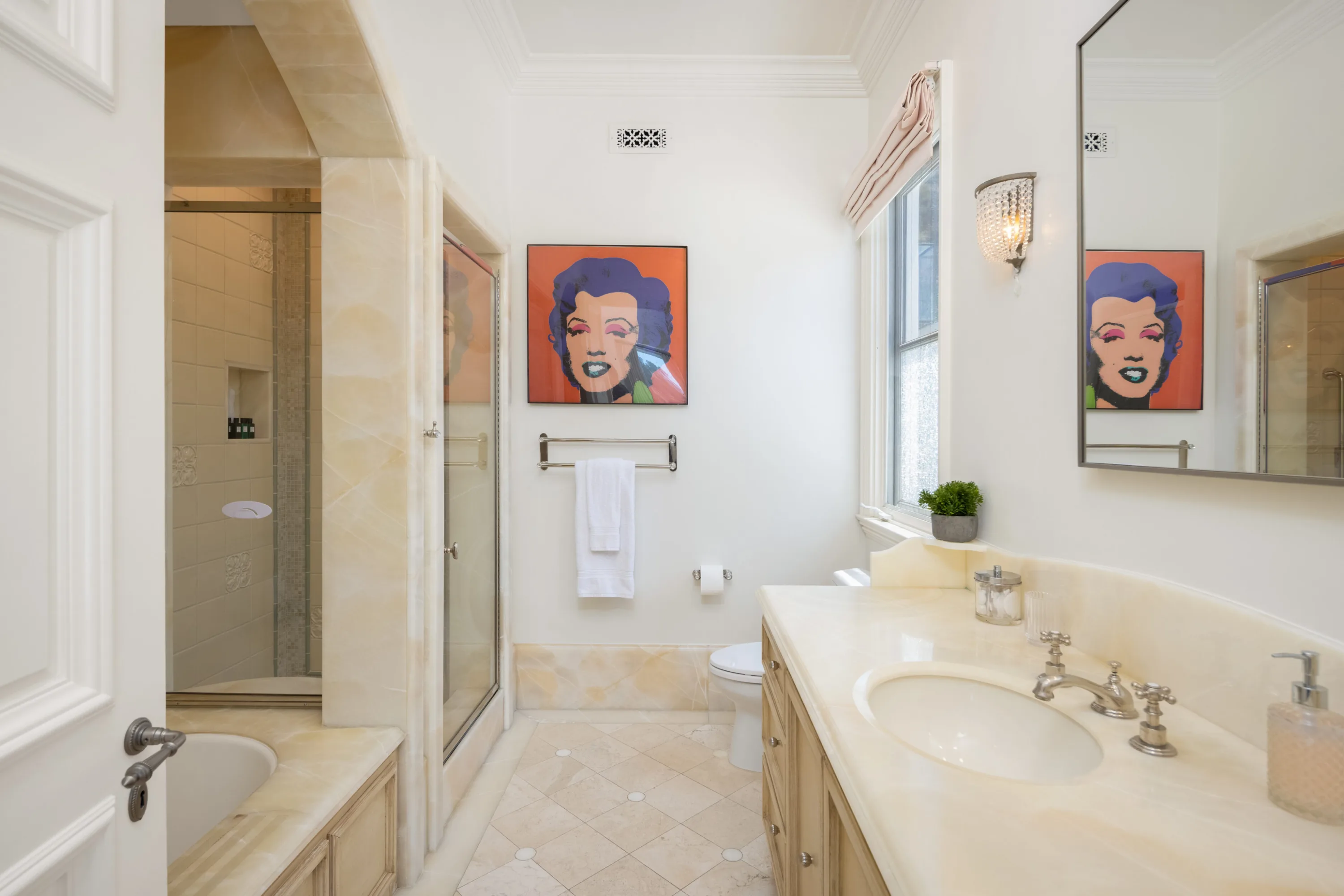 Onyx-toned guest bath with tub, glass shower and a pop-art portrait on the wall