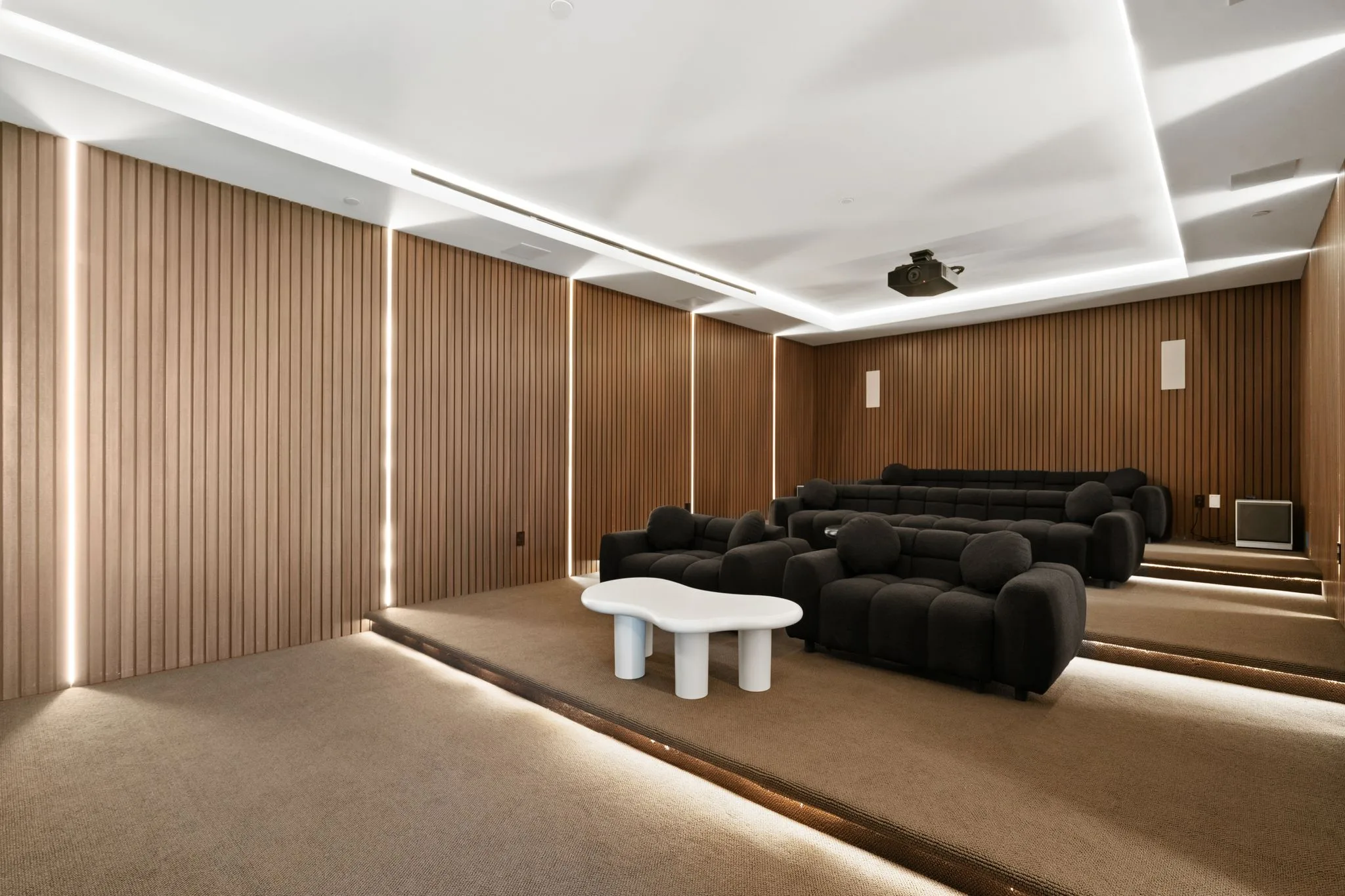 Tiered home cinema with plush black sofas, oak slat acoustic walls and ceiling projector