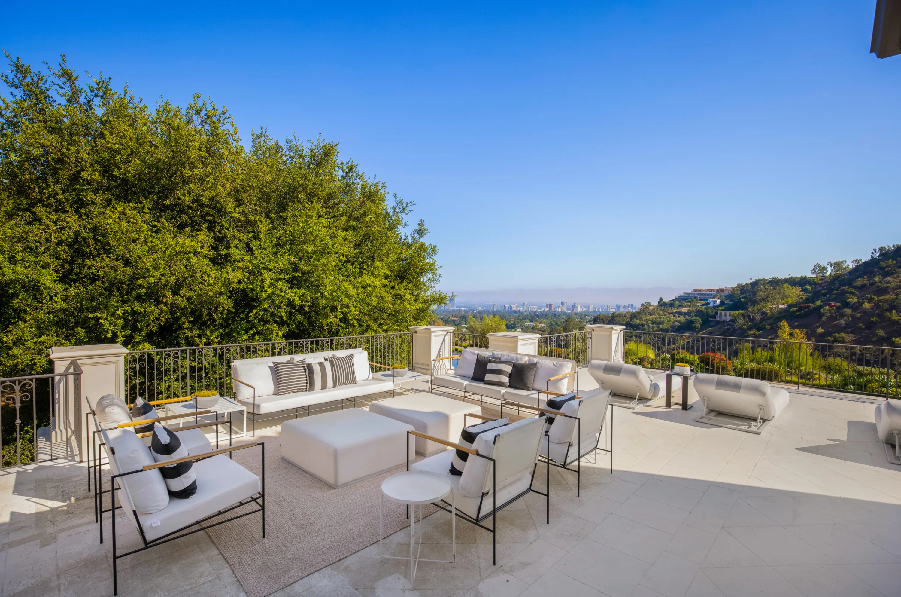 Upper terrace lounge with white sofas and armchairs above a railing, Century City skyline on the horizon