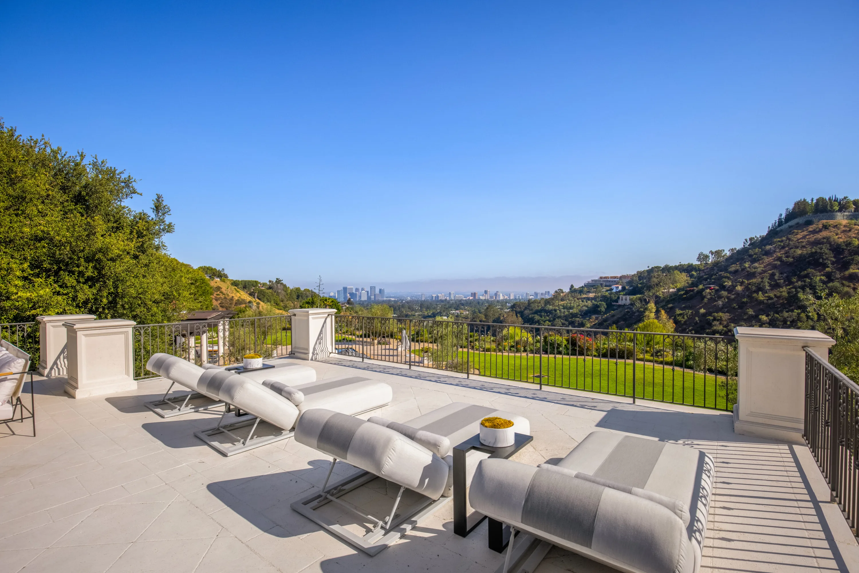 Sun loungers lined along the stone balcony terrace, overlooking the lawn, canyon slopes and distant downtown towers